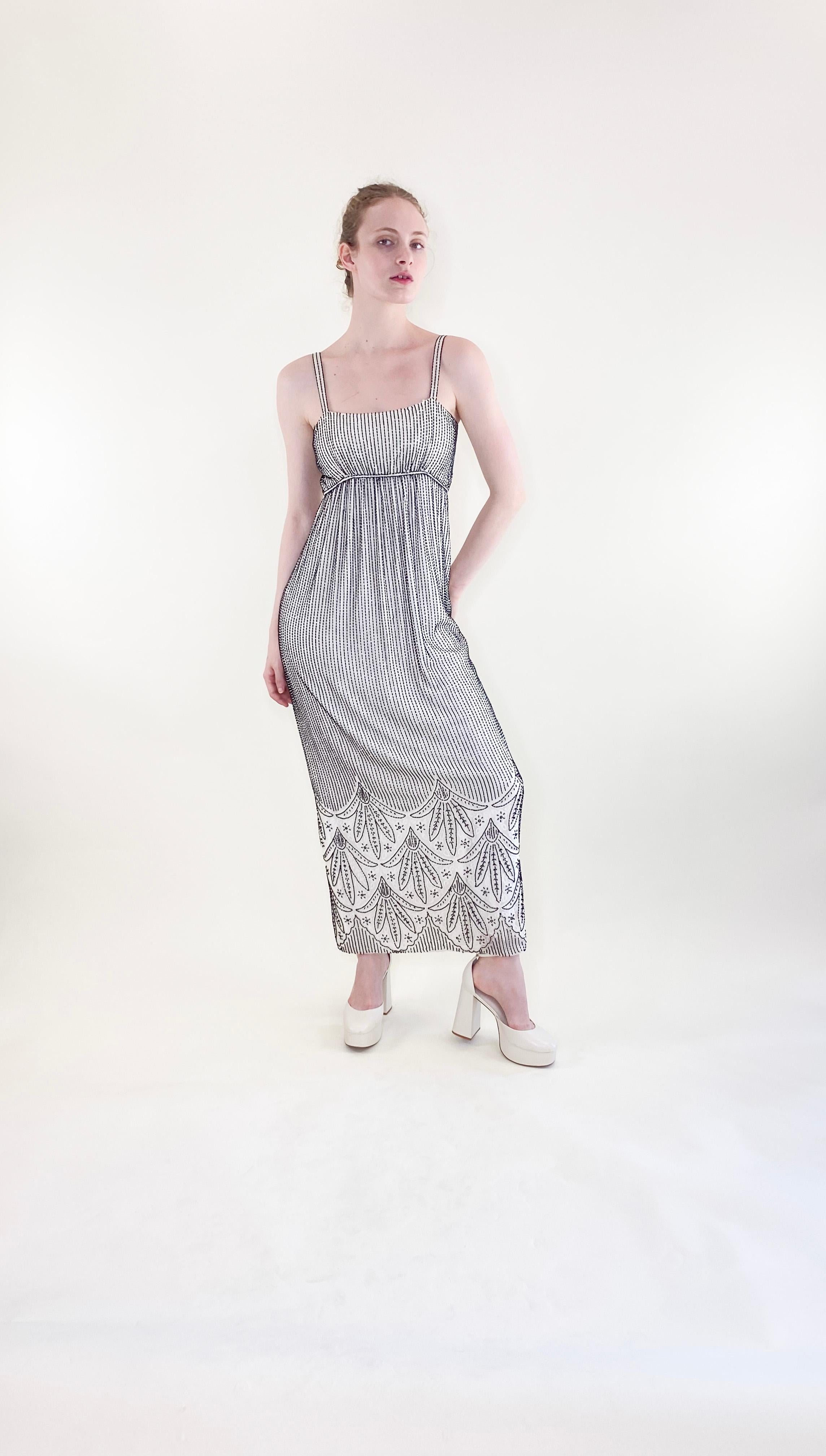 This vintage Alfred Bosand white gown with black beads and capelet is perfect for a special event. The elegant, beaded ensemble adds a touch of vintage charm to any occasion, making it a great choice for a vintage bride or anyone looking to make a