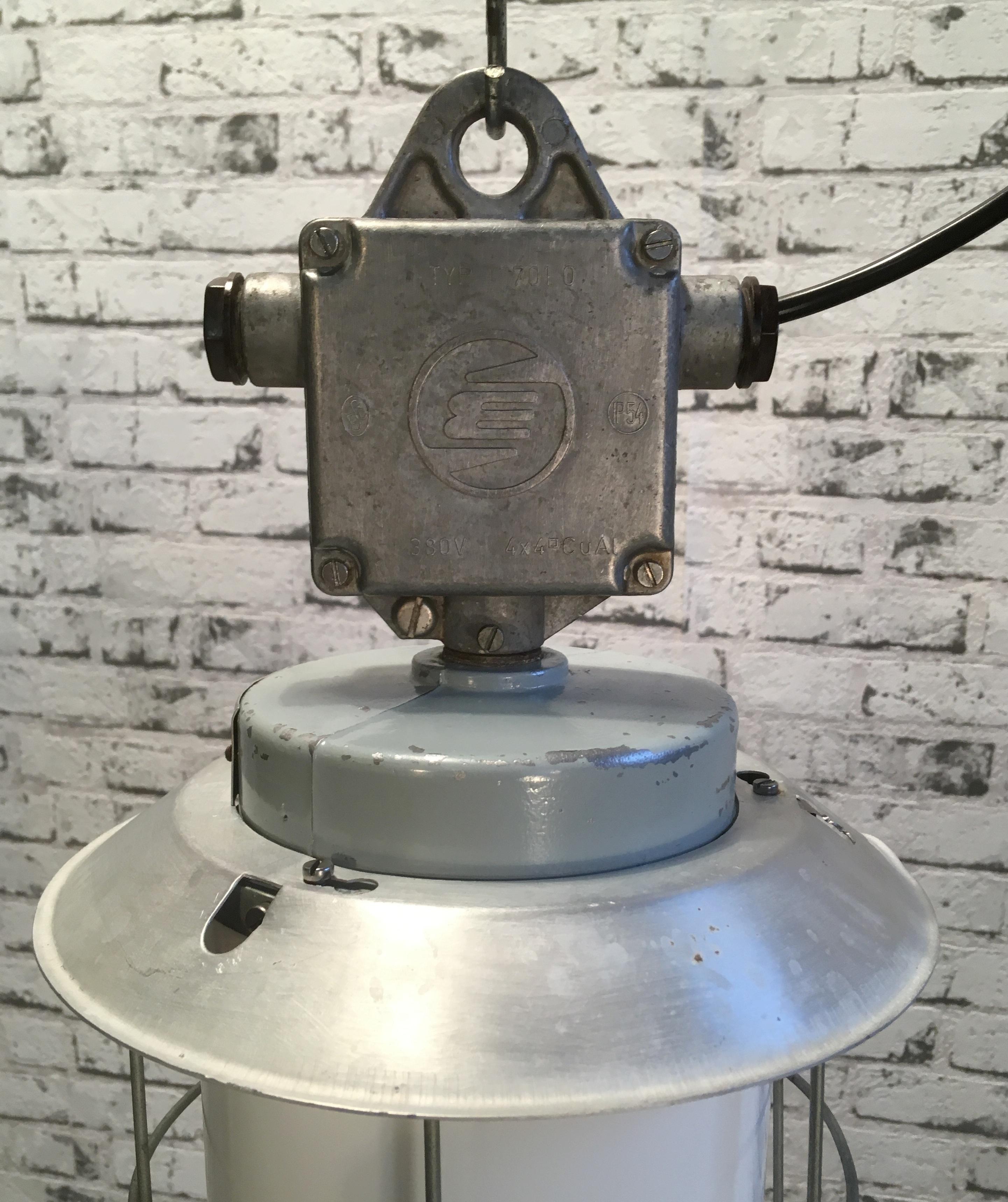 This industrial lamp in aluminium with milky glass was produced by Elektrosvit  in former Czechoslovakia during the 1970s . Iron cage. New porcelain socket  for E 27 lightbulbs and wire. Weight of the lamp is 2 kg.