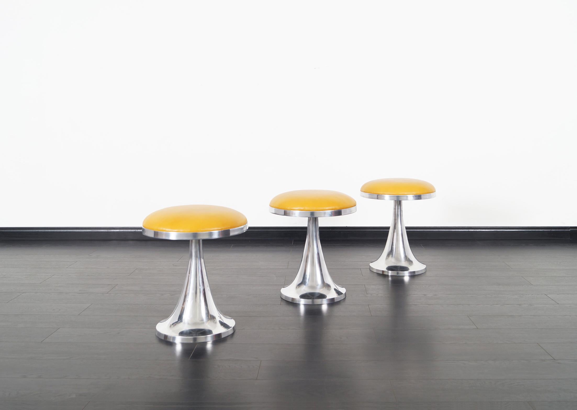 Set of three vintage aluminum stools. Newly reupholstered in this gorgeous butterscotch leather.