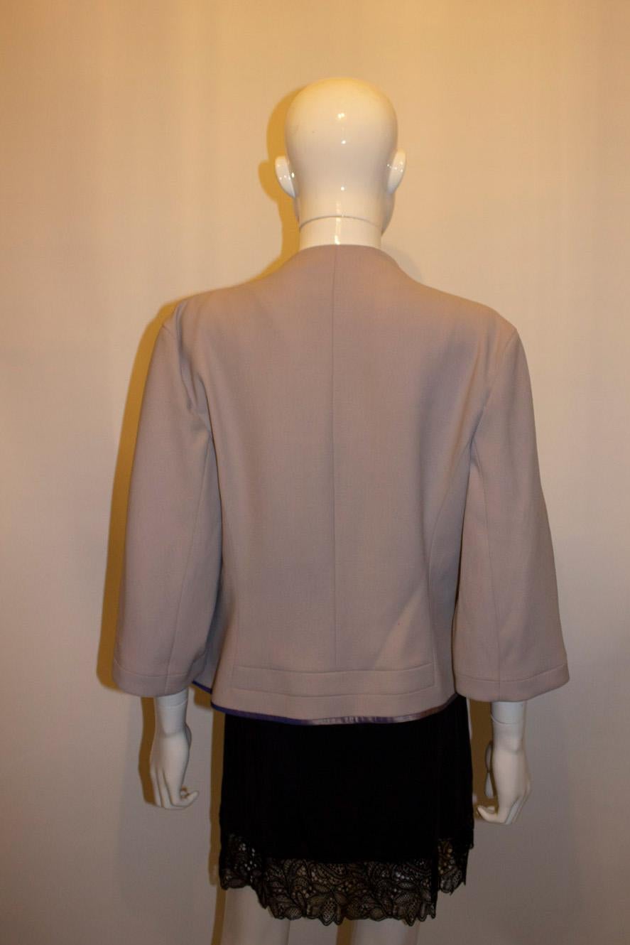 A pretty jacket for Fall, by Amanda Wakeley. In a silver /grey colour, the jacket has a round neckline. with ribbon detail at the hem. It is fully lined.  Made in Italy Size 14, Bust up to 38'',length 20''