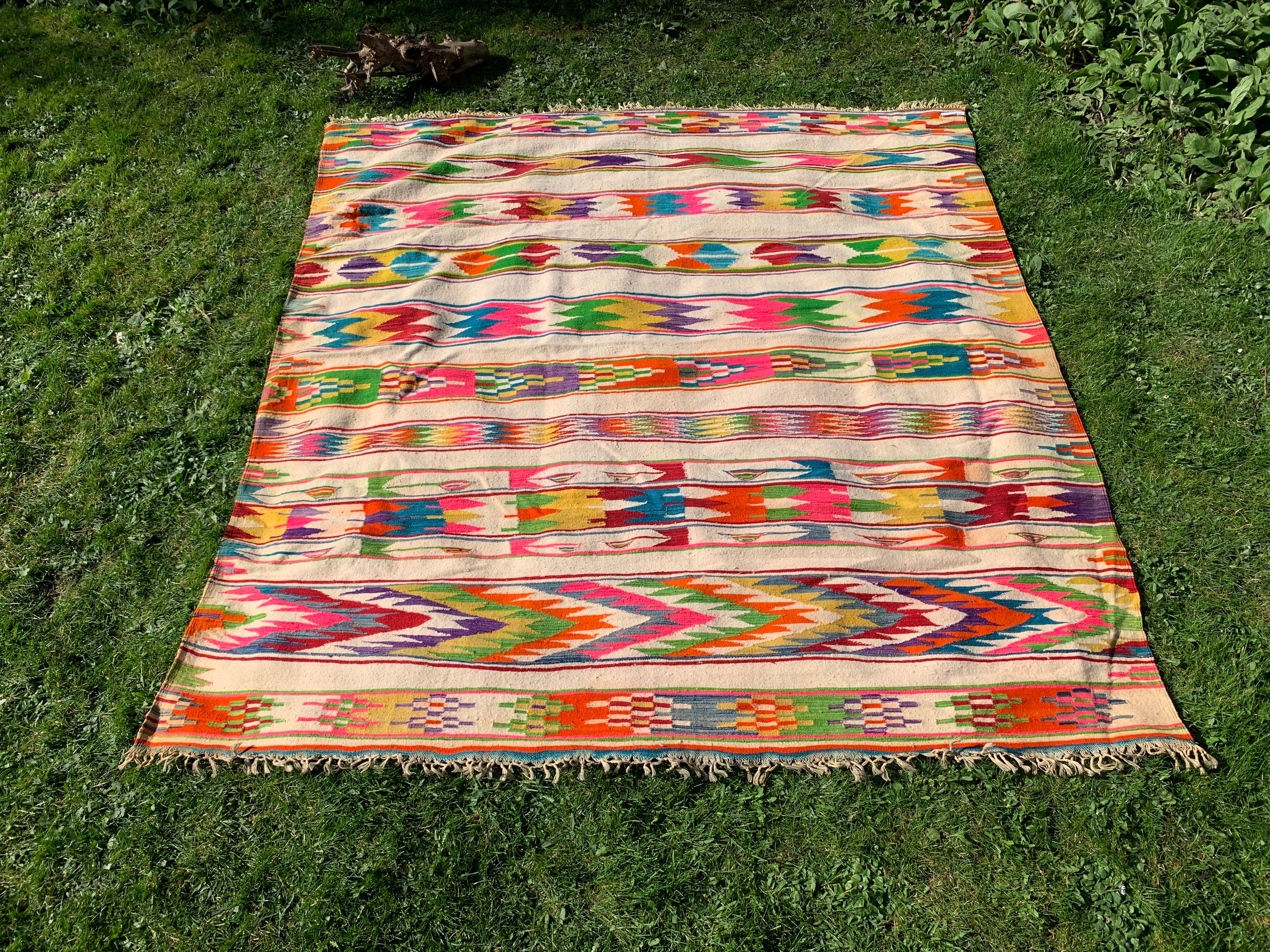 A vintage Berber 'Amazigh' multicoloured wool rug from northern Algeria is a beautiful and intricately crafted piece of textile art. The rug has a square shape and is double-faced, meaning that it can be used on either side. The base colour of the