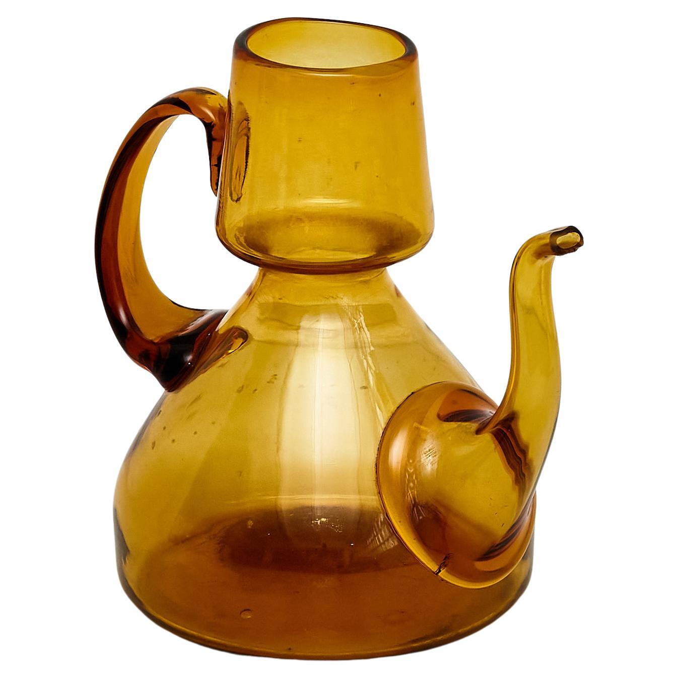 Immerse yourself in nostalgia with this beautiful amber blown glass oil cruet dating back to around 1940. This charming piece is a testament to mid-20th-century craftsmanship, evoking the warmth of a bygone era.

The subtlety of the amber blown