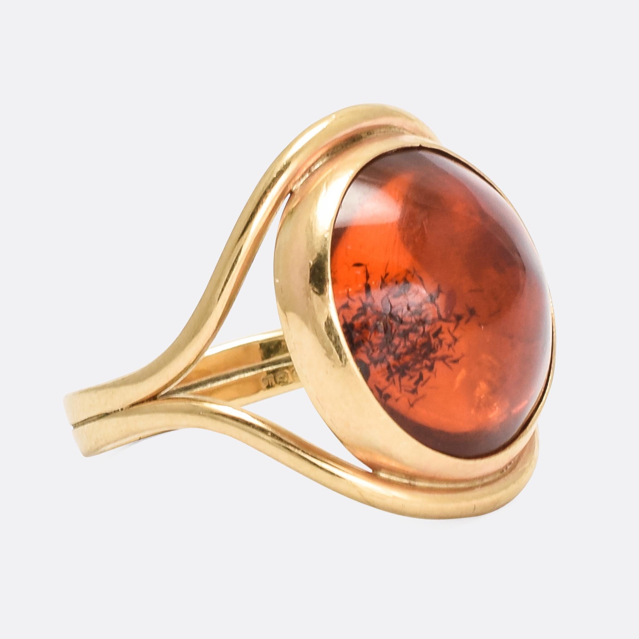 A cool vintage single-stone ring dating from the early 1990s. The principal stone is a gorgeous amber cabochon, collet set with foil behind that reflects the light back through the stone making it appear to glow from within. The double band splits