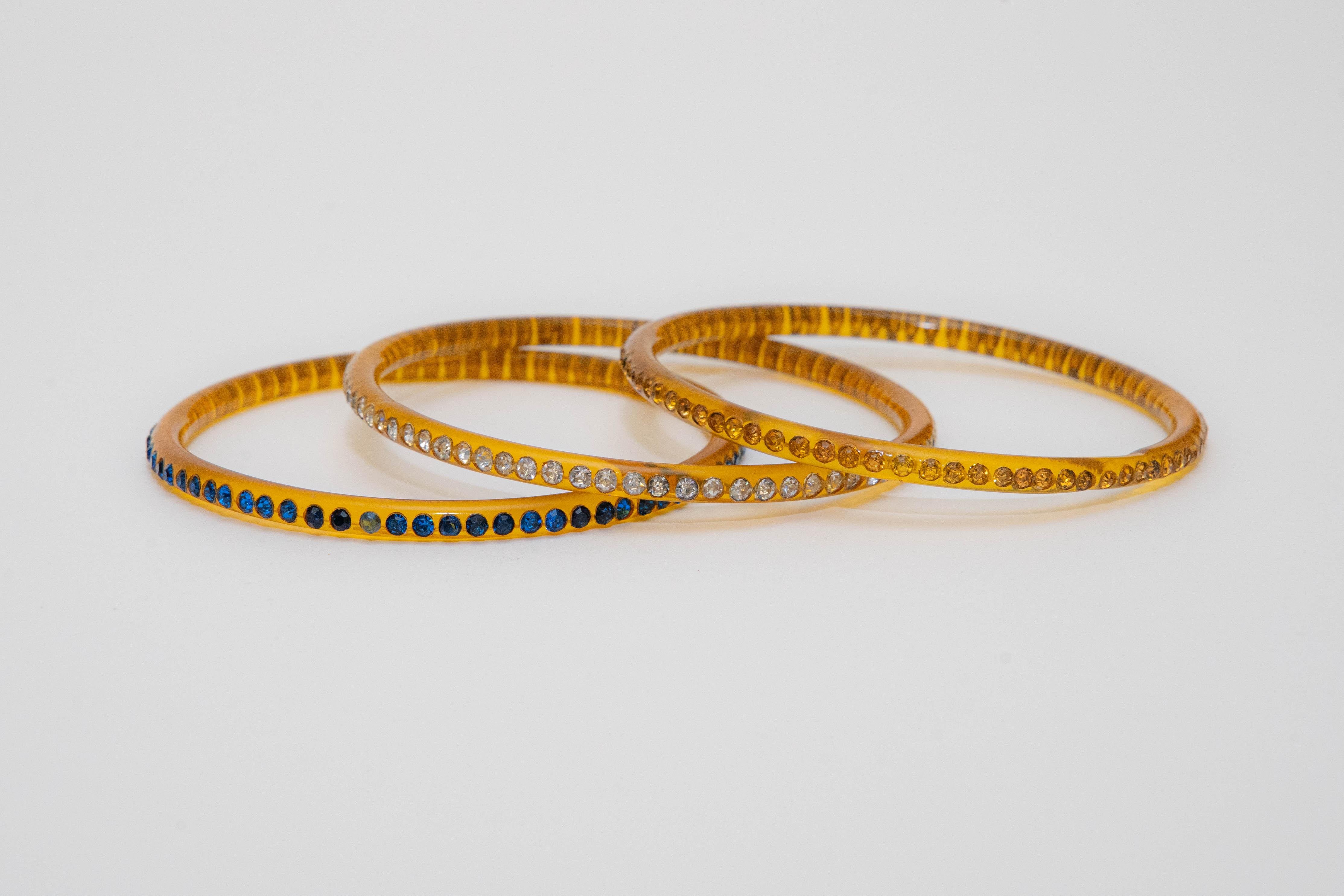 This vintage set of 3 amber colored celluloid bangle bracelets have different colored rhinestones. They are each razor thin and will only fit a size 6 or max 6.5 wrist. From the 40's. Celluloid is a plastic that looks like bakelite. The rhinestones