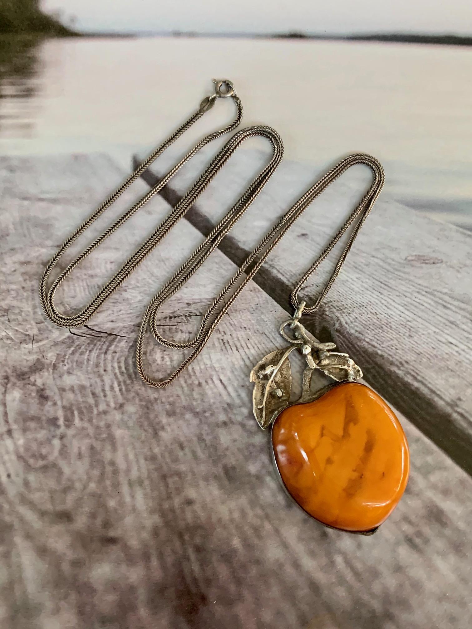 This unique Amber Fruit-shaped pendant is adorned with sterling Silver and hangs from a 32