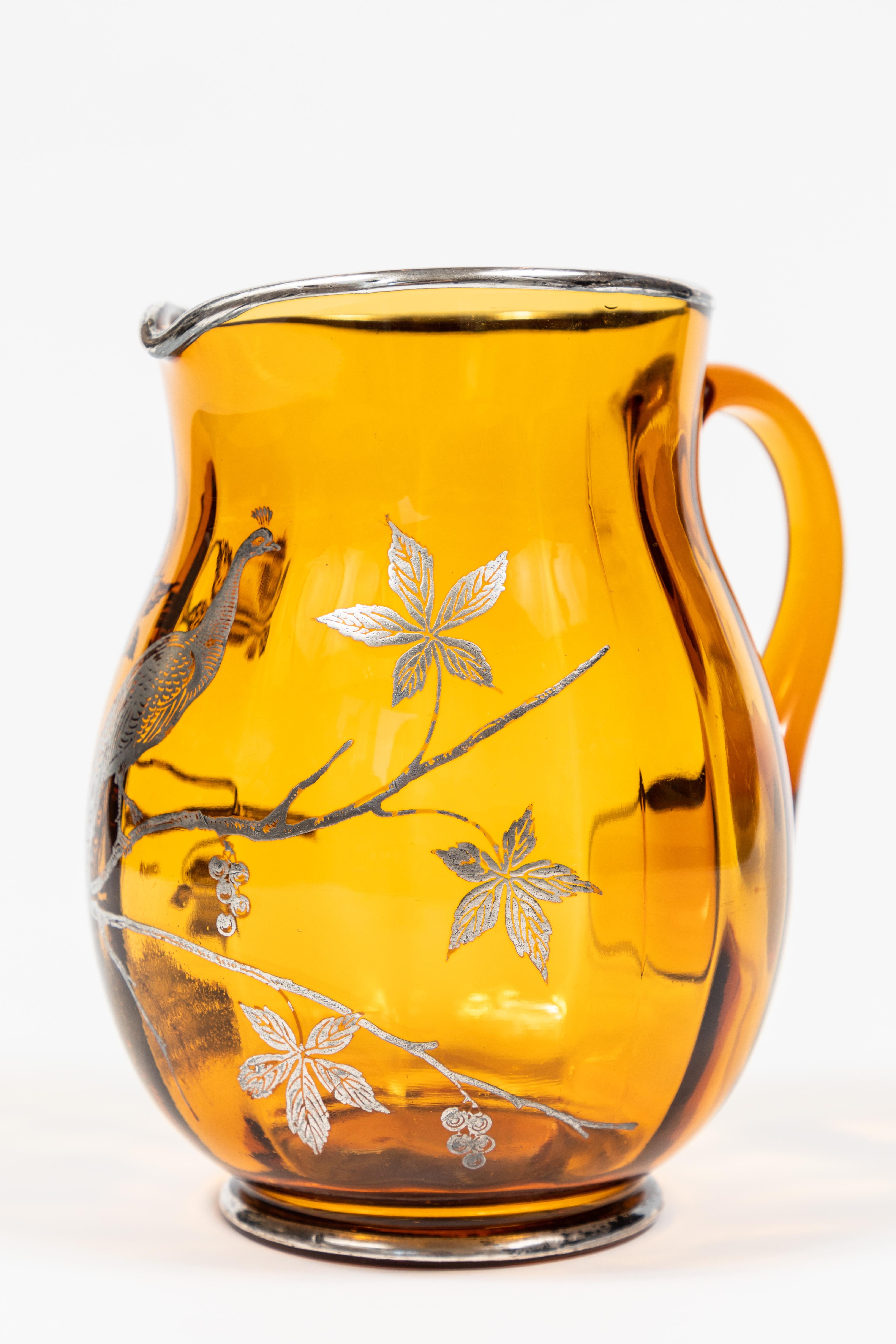 Vintage amber glass pitcher with sterling silver overlay of peacock on a branch. Pitcher is marked 'sterling', as shown in photo.
