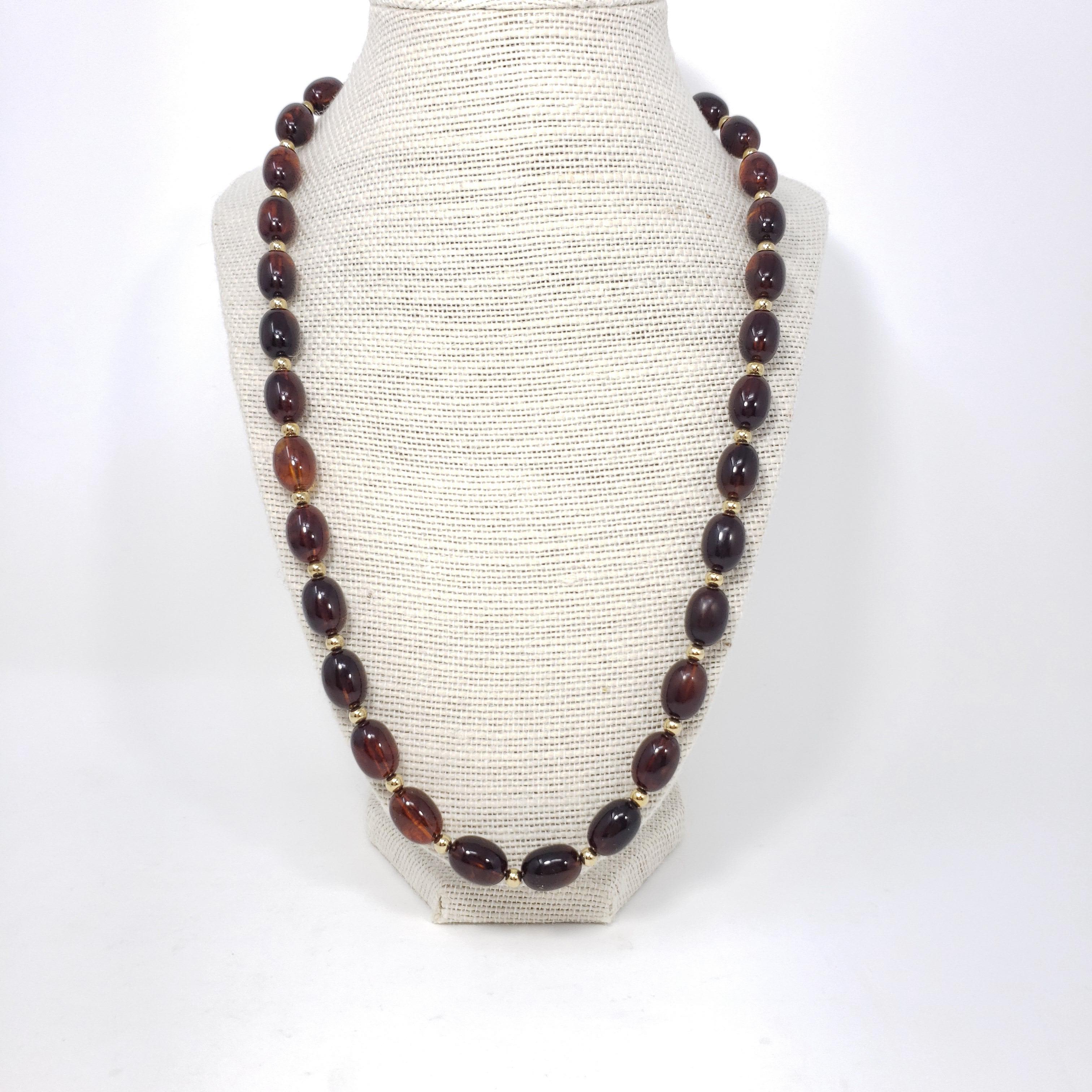 A retro necklace featuring amber-colored lucite beads with gold-tone accents. A perfect touch of vintage flair!