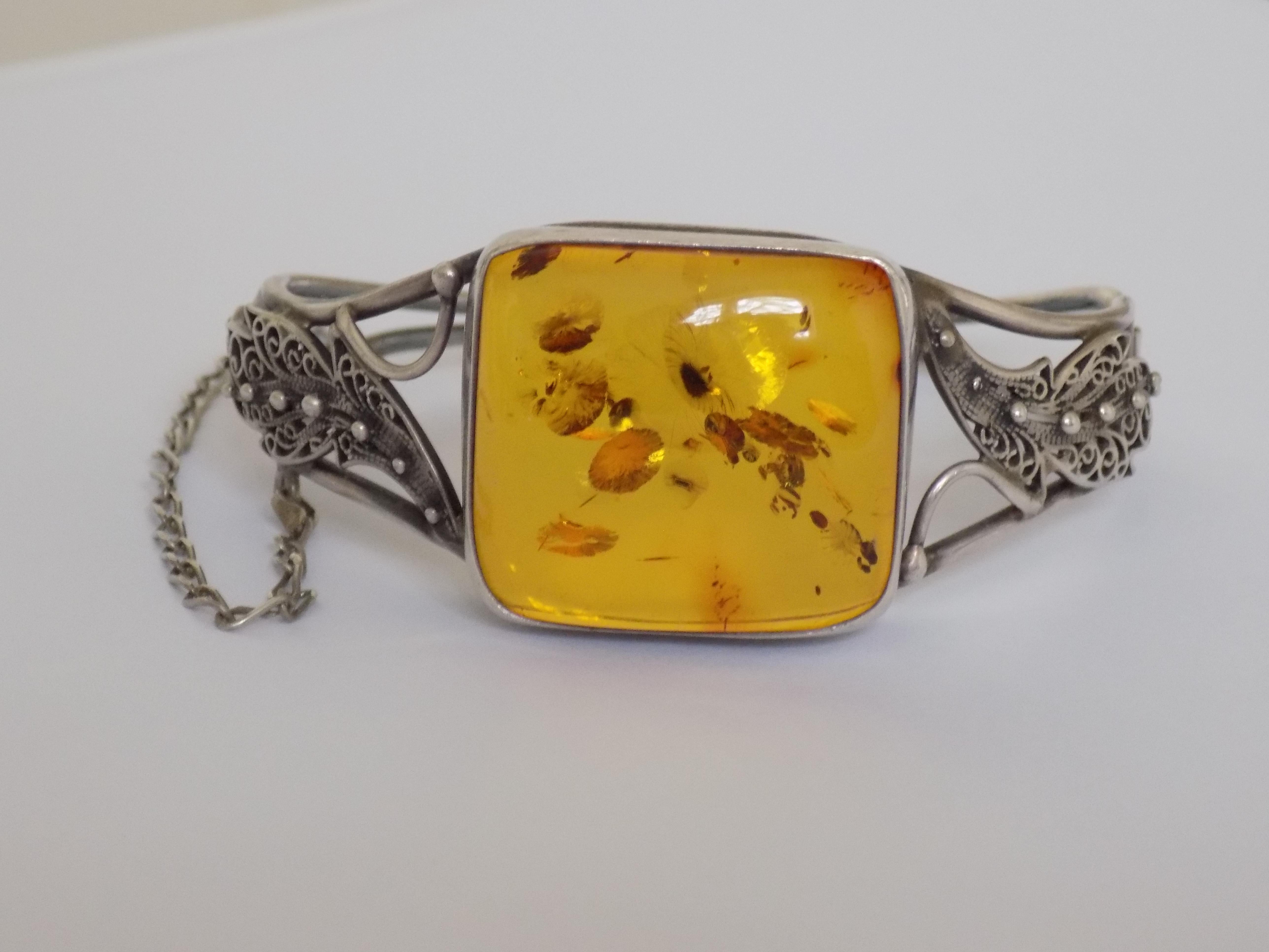 A Lovely Vintage Sterling Silver and Amber bangle. The bangle made in Art Nouvea style. 
The bangle with beautifully crafted Silver Filigree Leaf Motif on the ends.

Diameter inside of the bangle 60mm,
Width of the front 27mm, back 4mm.
Weight