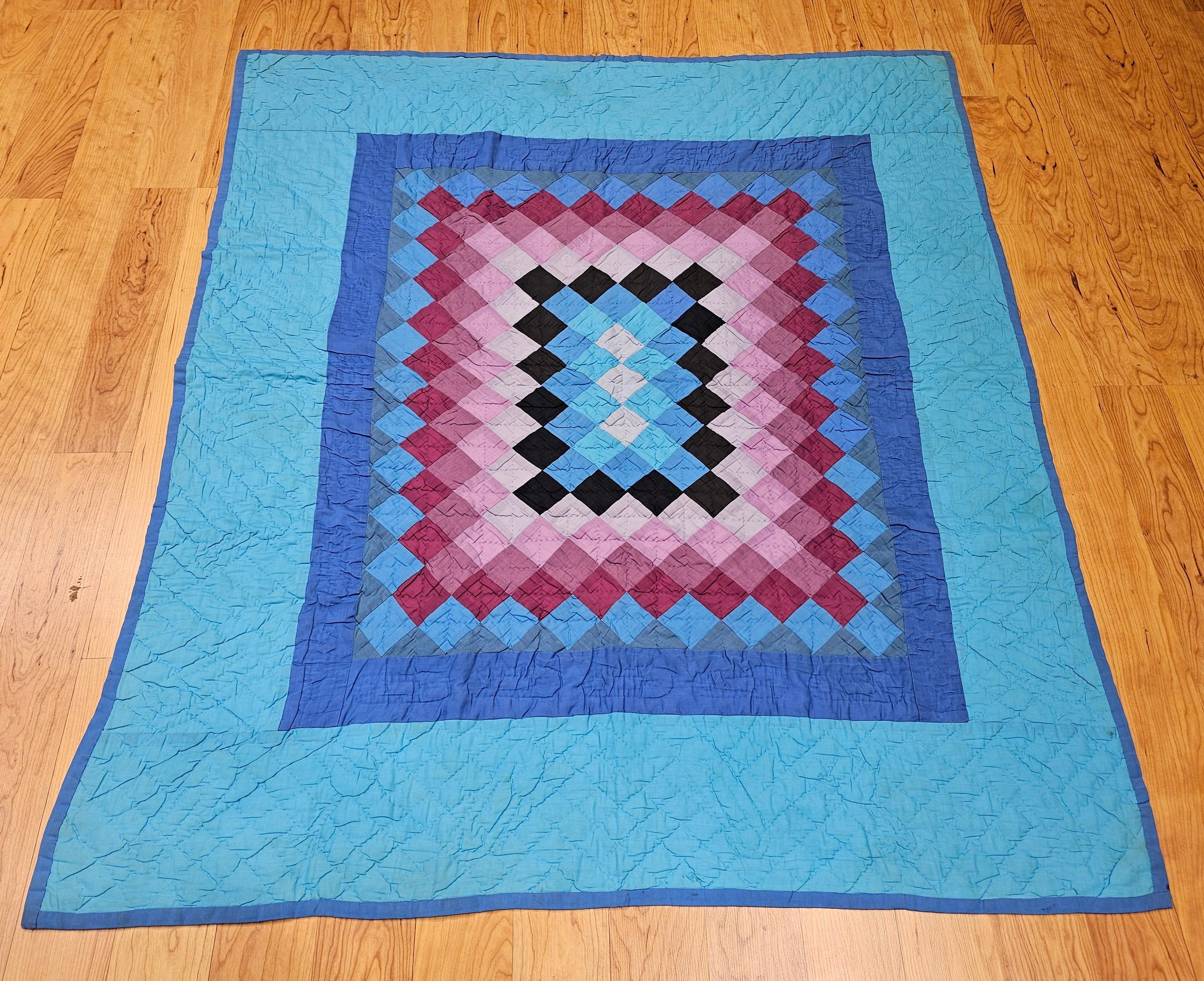 A visually captivating mid-20th century Amish quilt from Lancaster County, Pennsylvania, expertly hand-crafted in the traditional “Sunshine and Shadows” pattern. This vibrant patchwork design features a striking interplay of blue and green tones,