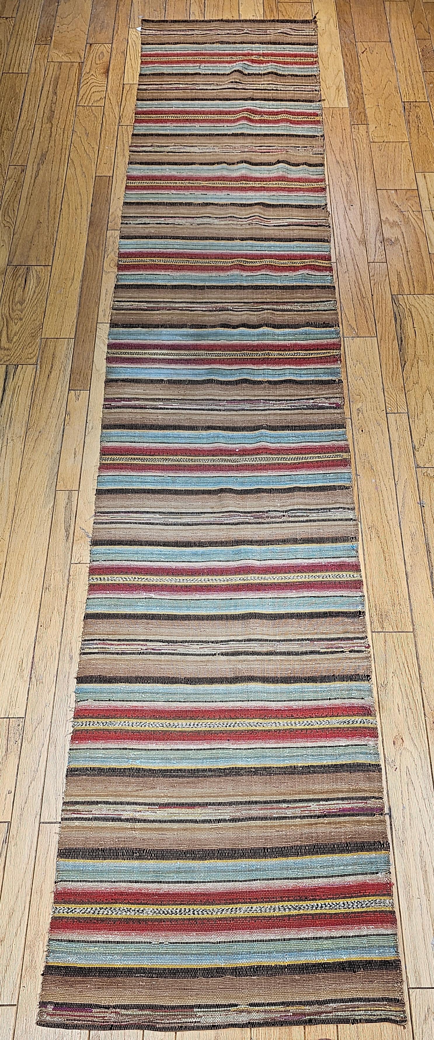Vintage American Amish Rag Runner is in stripe design.  The Amish Rag Runner has a stripes pattern in sage green, red, chocolate,  brown, and orange colors.  The Amish community in Pennsylvania wove these runners mainly for their own use using the