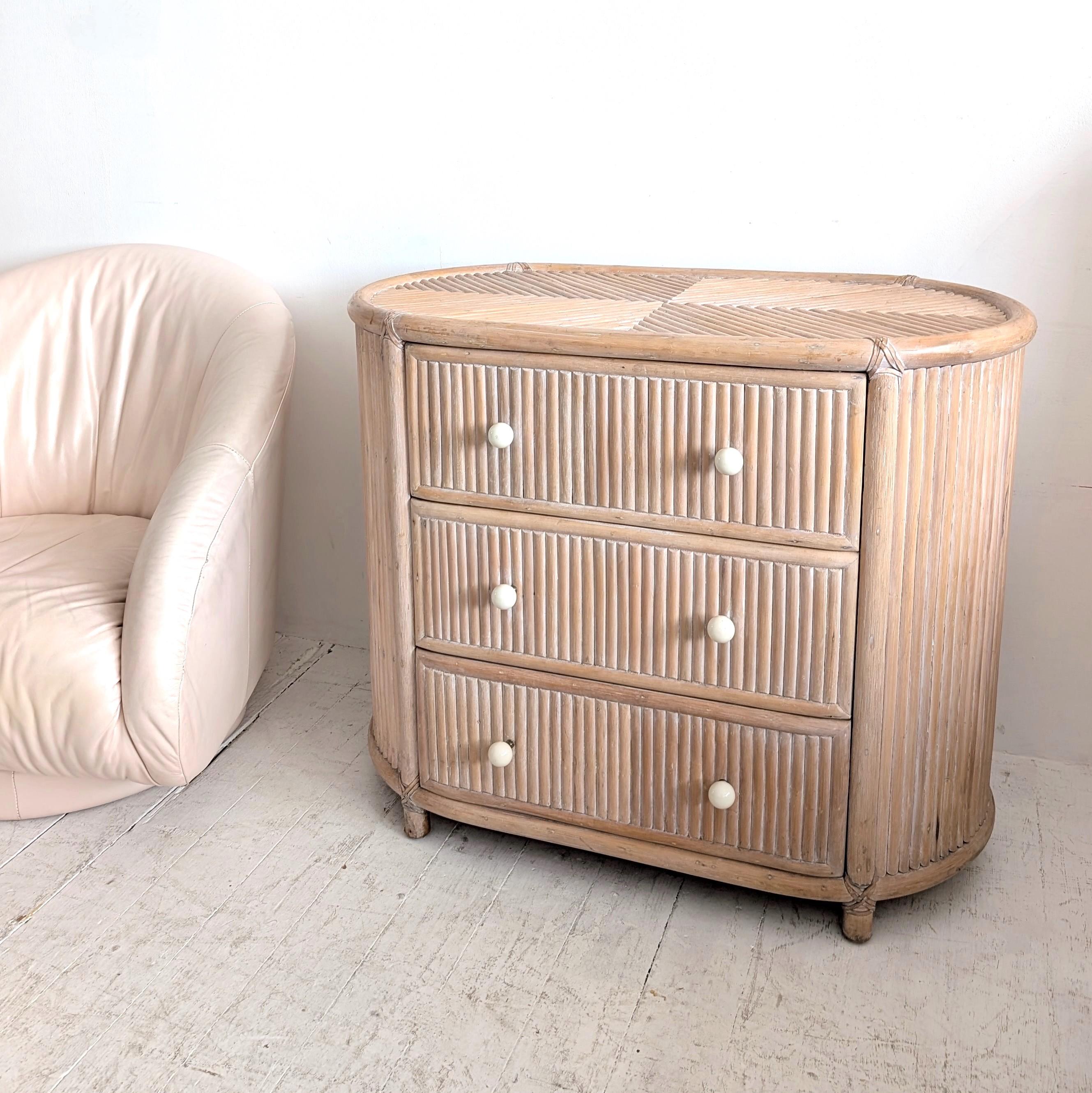 Meuble à tiroirs elliptique vintage américain en canne blonde. Trois tiroirs avec poignées boule en porcelaine.

Dimensions : largeur 95cm, profondeur 49.5cm, hauteur 77.5cm