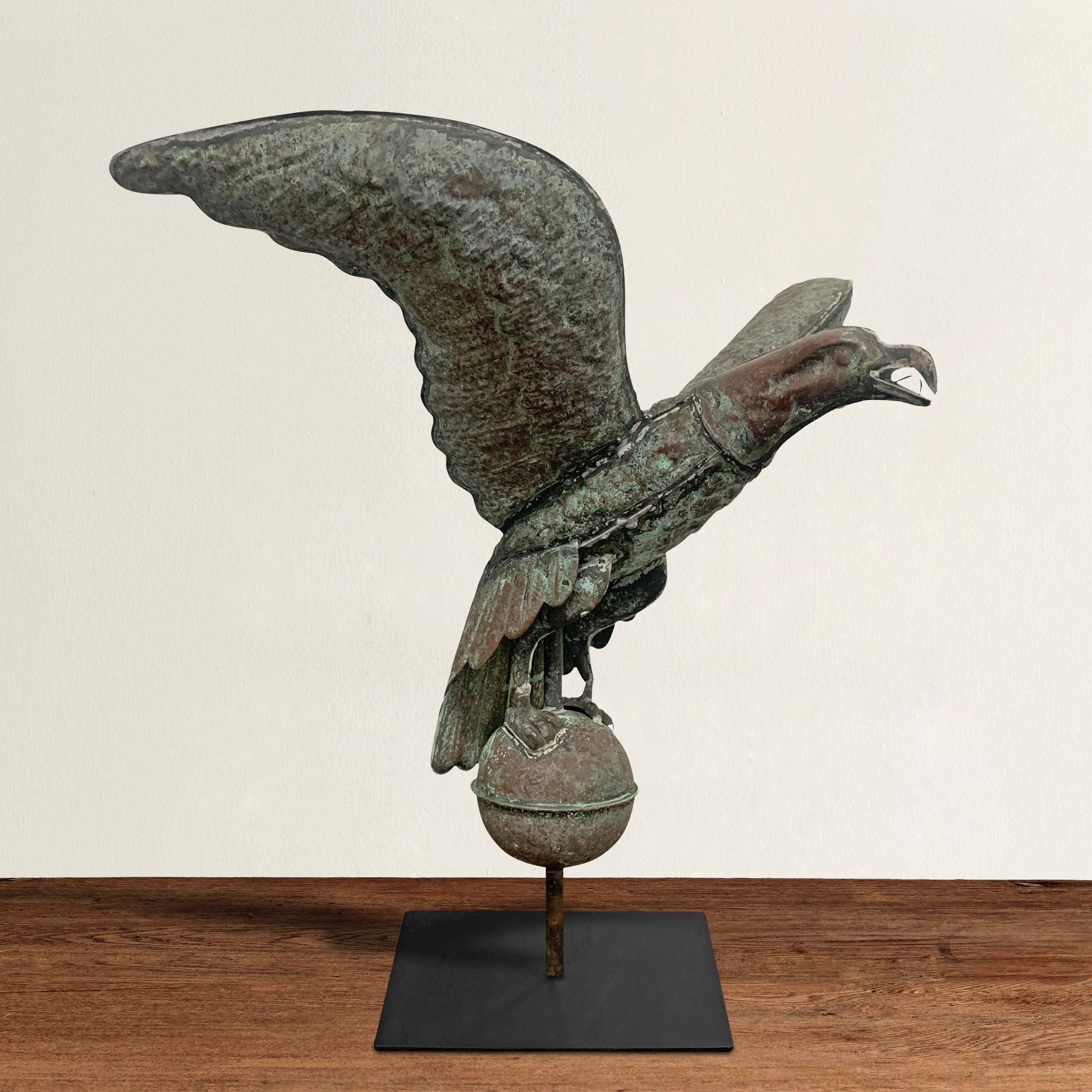 A wonderful vintage American hand-hammered copper weathervane depicting a Bald Eagle with wings spread and perched atop a sphere, all with a wonderful patina and mounted on a custom mount.