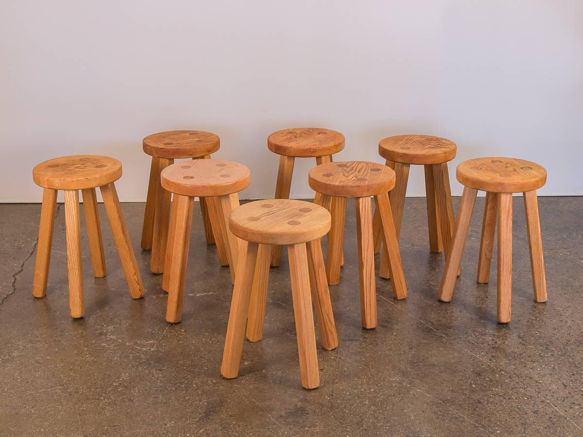 We have eight four-legged American Craft stools constructed from warm, natural oak. Priced per piece. Simple dowel joinery construction is attractive and are solid and sturdy. Stools are in good condition, each owning varying degrees of