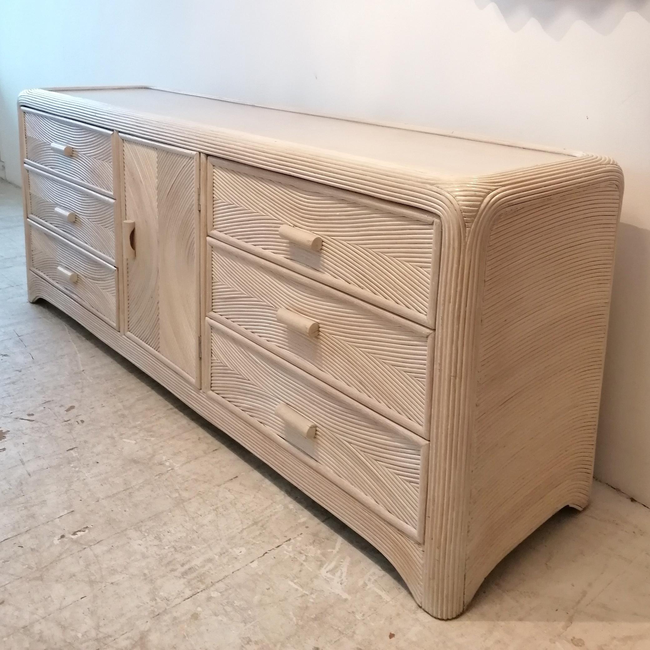 A vintage American pencil reed sideboard with drawers. Central cabinet door reveals 3 more internal drawers.
Blonde wood top, wood-lined drawers.

Dimensions: width 188cm, depth 50cm, height 75cm
