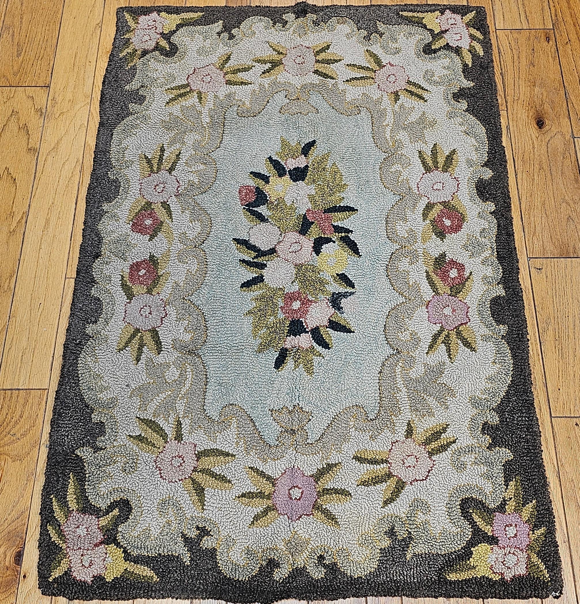 Beautiful hand-hooked area rug from the mid 1900s.  The rug has a floral pattern set in a pale green background.  The center medallion is a bouquet of flowers in pastel color including pale green, yellow, ivory and pink.  The edge of the rug is a