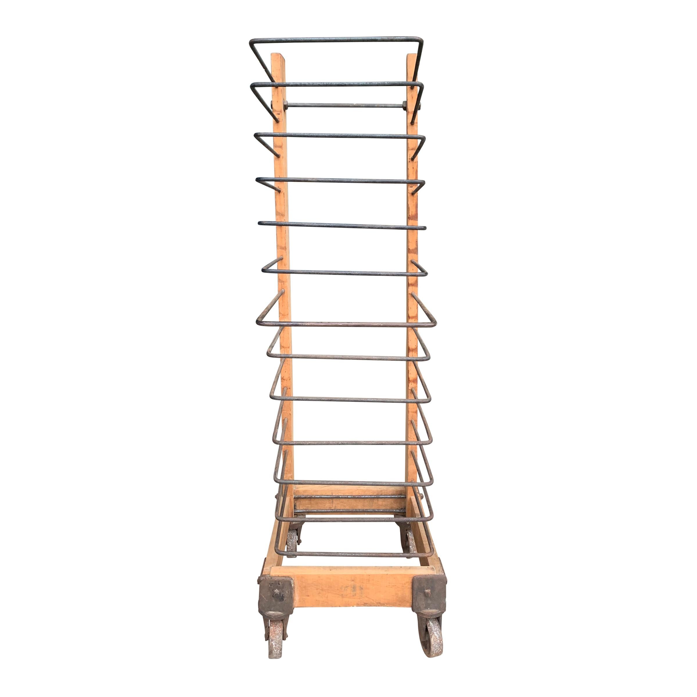 A super cool vintage American industrial baker's rack with two tall pine uprights supports U-form iron bars that originally held trays. Four large iron casters on the bottom. Adding glass shelves would complete this piece!