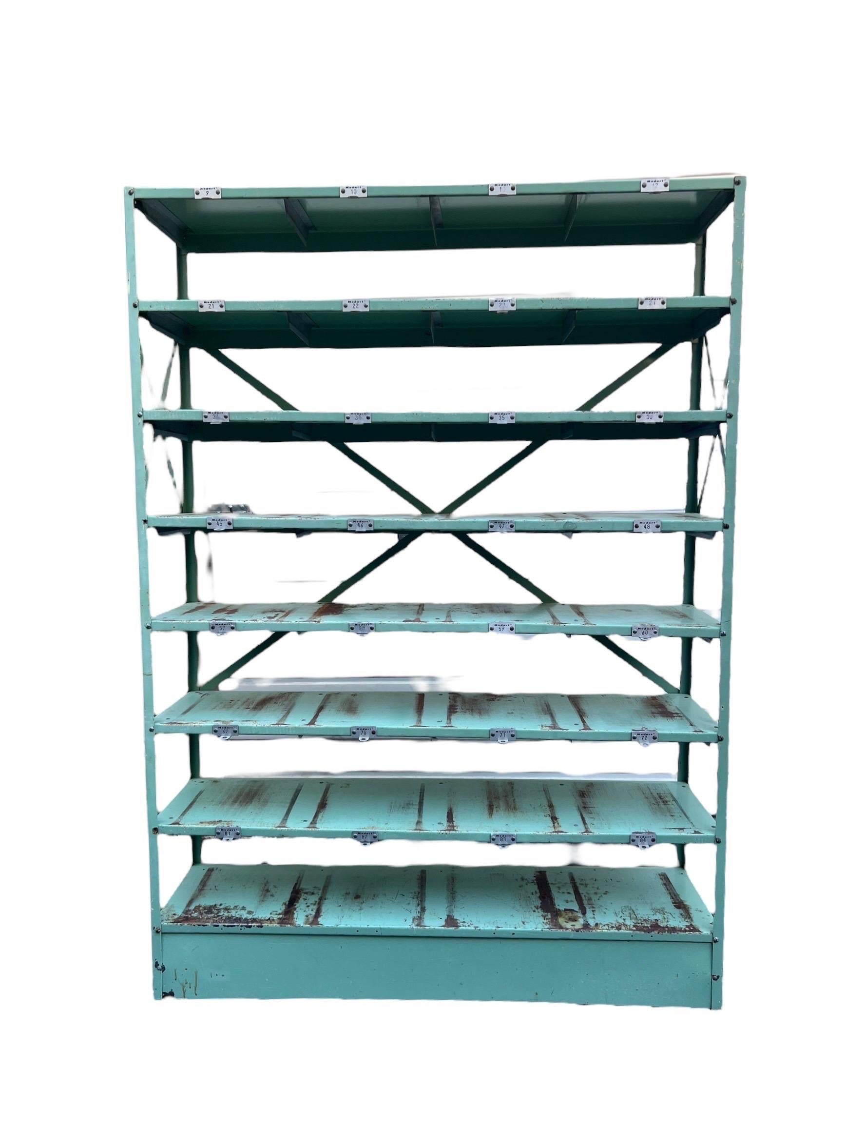 Industrial Metal Shelf Unit, Green Patina. This is a hardy and heavy industrial, rolling shelving unit. It has 7 compartments. It is painted green with great patina. Would look great in a shop, in a greenhouse, or your home.

Dimensions - 52W 14D