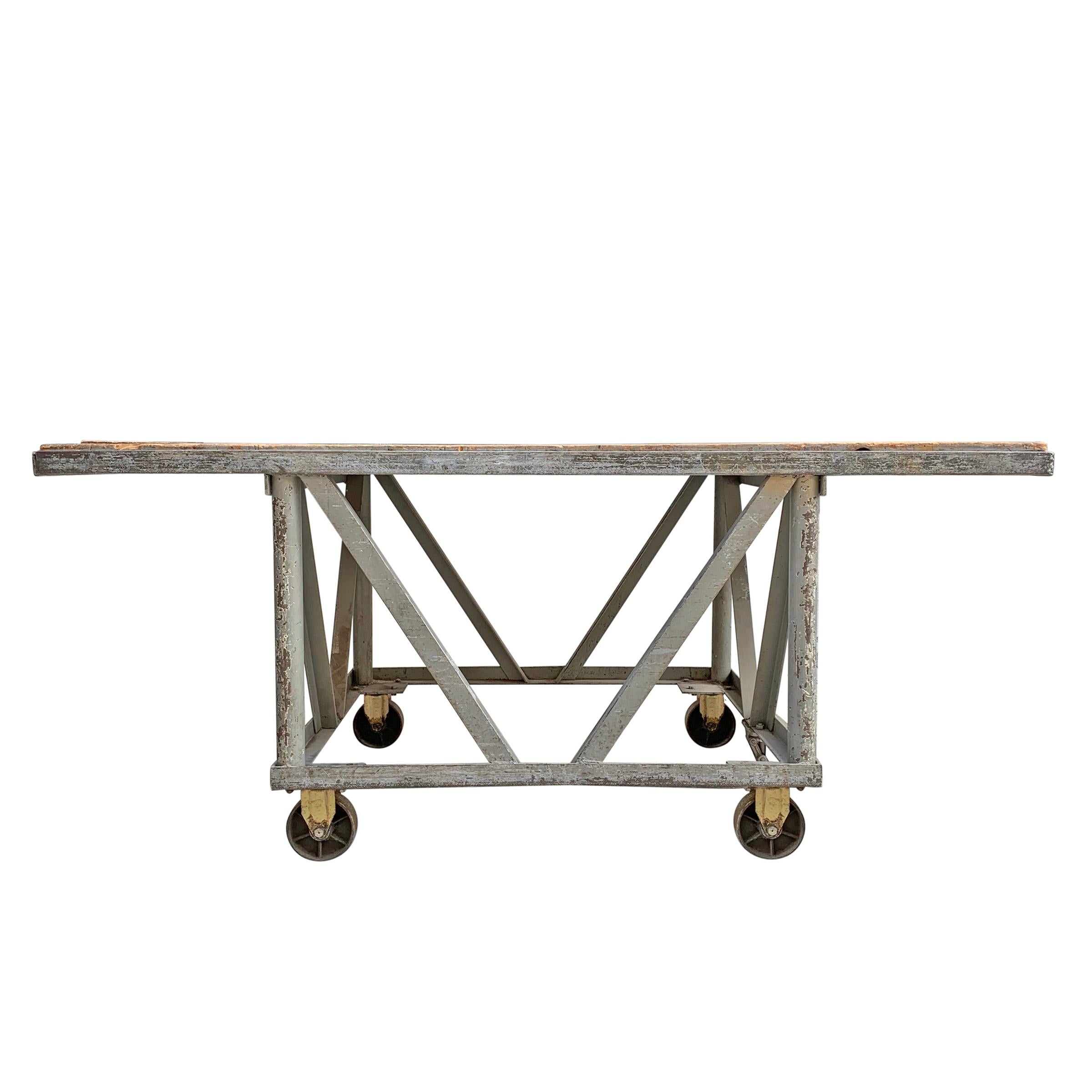 An incredible vintage American industrial table on large iron casters with a plank wood top with a wonderful well-worn surface. A locking mechanism on one side locks the piece in place. We can't wait for someone to place this in a kitchen! It