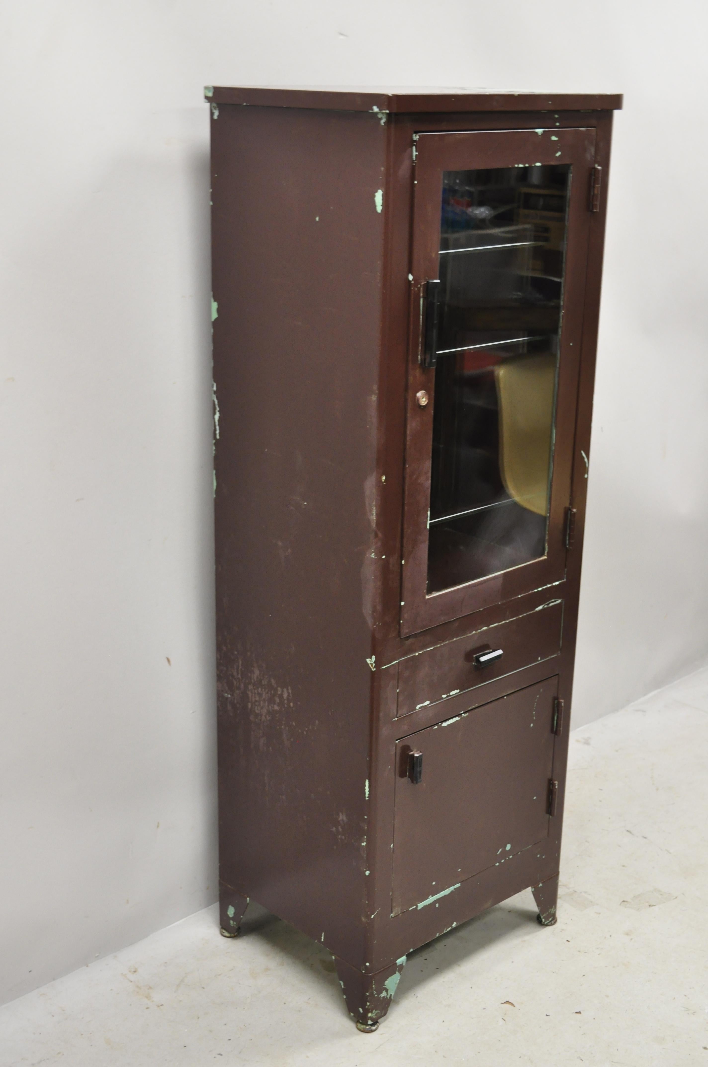 Vintage American Industrial steel metal narrow medical dental bathroom cabinet. Item features 3 glass shelves with rounded edges, nice narrow size, 2 swing doors, 1 drawer, very nice vintage item, quality American craftsmanship, circa mid-20th