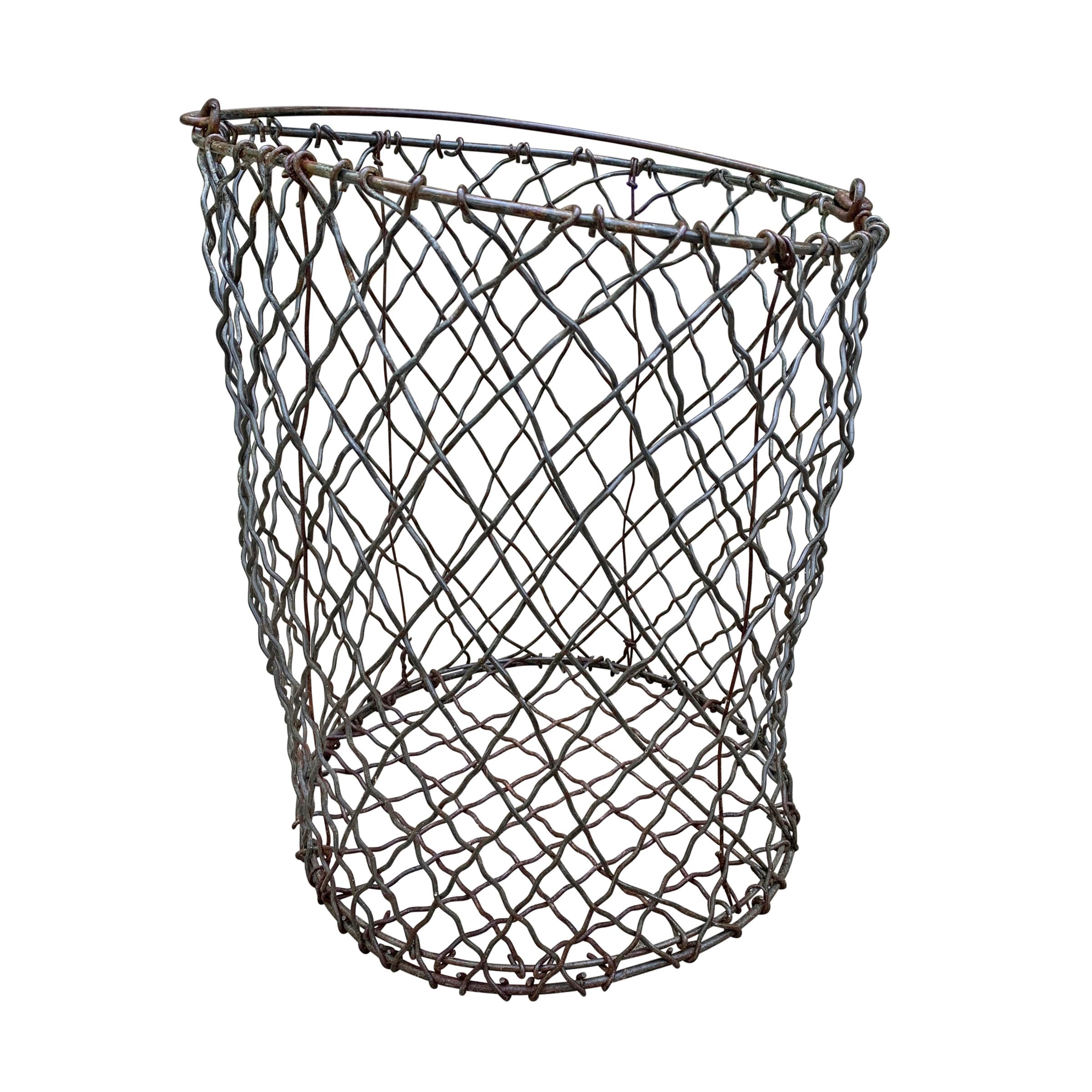 A wonderful vintage American industrial woven wire basket of round form with a handle, and groovy wonky form. Perfect for a waste paper basket in a powder room, or catchall for gloves and scarves by your front door.