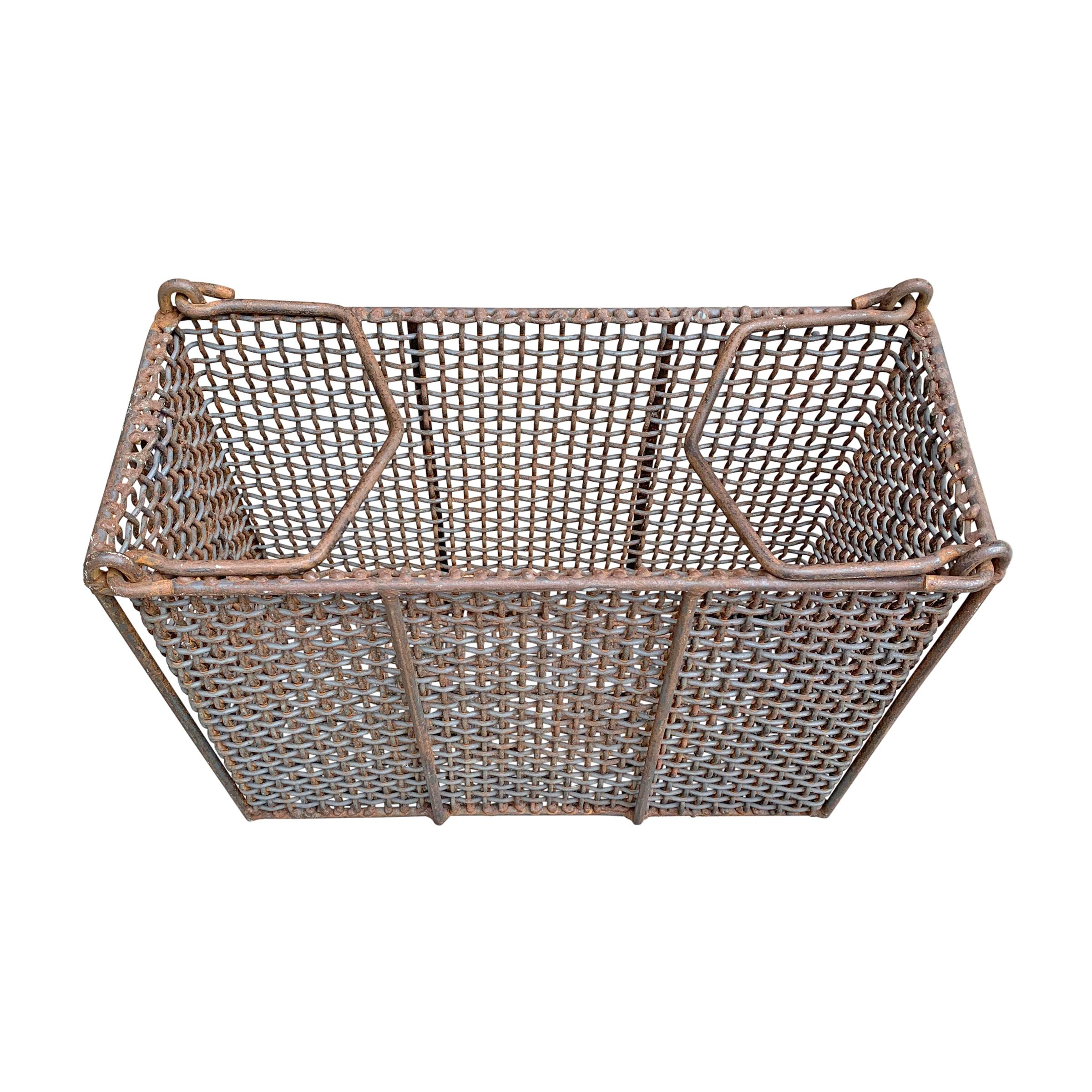 A fantastic early 20th century American Industrial woven wire basket with two handles that fold in or out. Such a cool form and perfect for use as a waste paper basket that requires a narrow space.