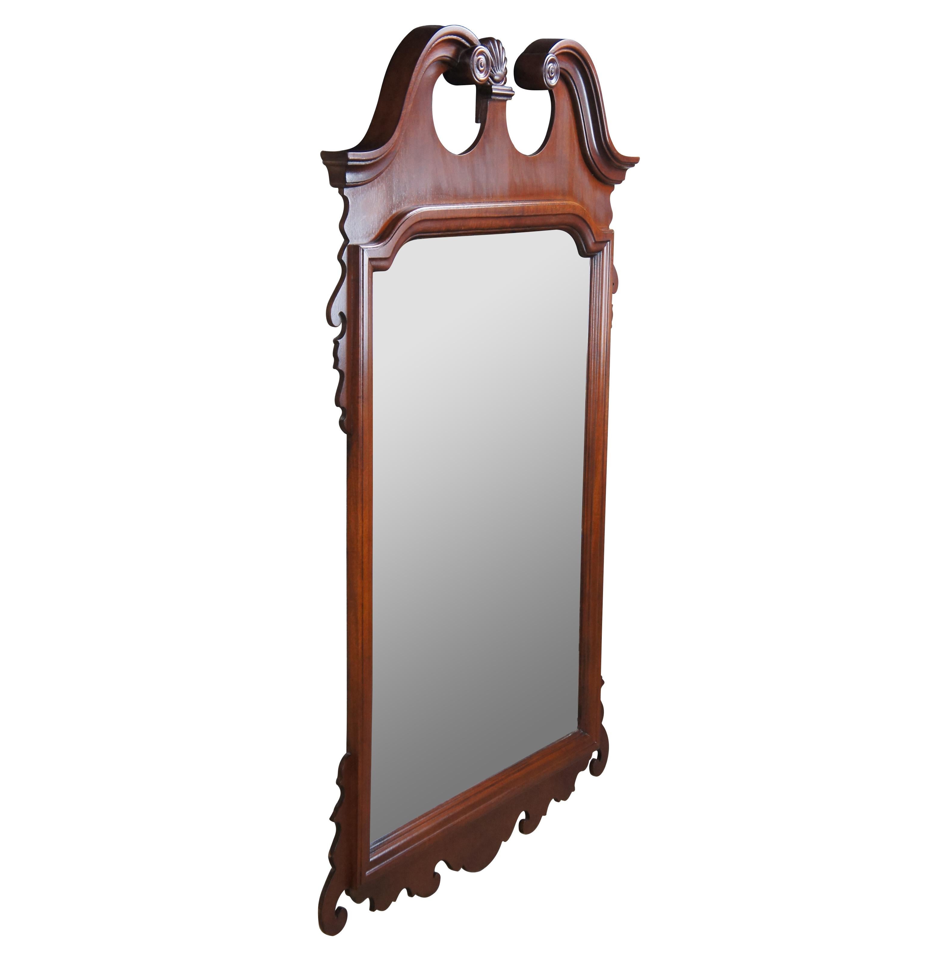 Vintage Chippendale style mahogany mirror. Beautifully designed with a scalloped finial between open pediment. The frame features elegant scrolling. The glass plate is beveled. Marked along the back made in USA. Measure: 50