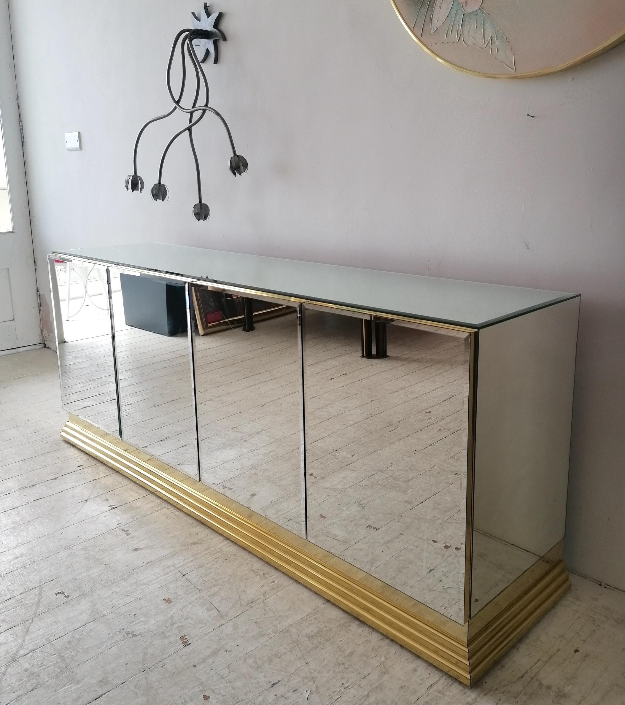 A stunning mirrored sideboard by Ello Furniture, USA 1980s. Bevelled mirror glass doors and top, gold metal plinth base. Inside are 2 adjustable shelves. 
There's a small 2cm area with loss of mirror silvering (not a chip) see detail photos.

We
