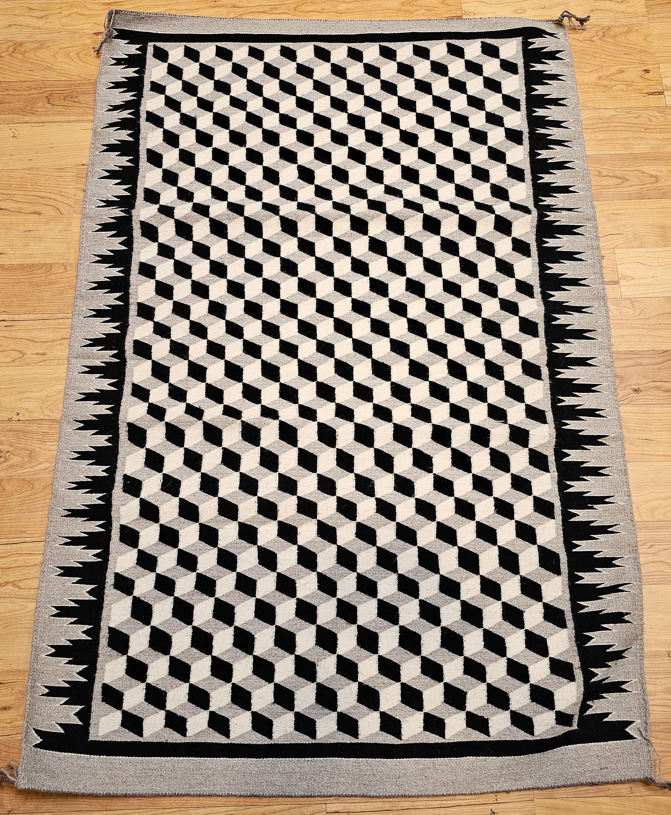 Verleihen Sie Ihrem Raum einen Hauch von kulturellem Erbe und visueller Faszination mit diesem Vintage-Teppich der amerikanischen Ureinwohner Navajo, der das fesselnde Muster Tumbling Block in warmen Elfenbein-, Braun- und Grautönen zeigt. Dieses