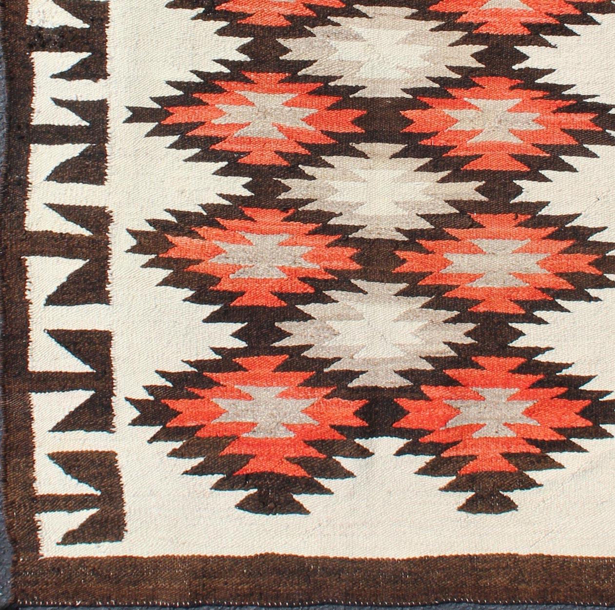 Vintage American Navajo Tribal rug with diamonds in brown, orange and ivory
This intriguing vintage Navajo rug was woven in the United States during the first half of the 20th century. The exciting and unique composition boasts a captivating