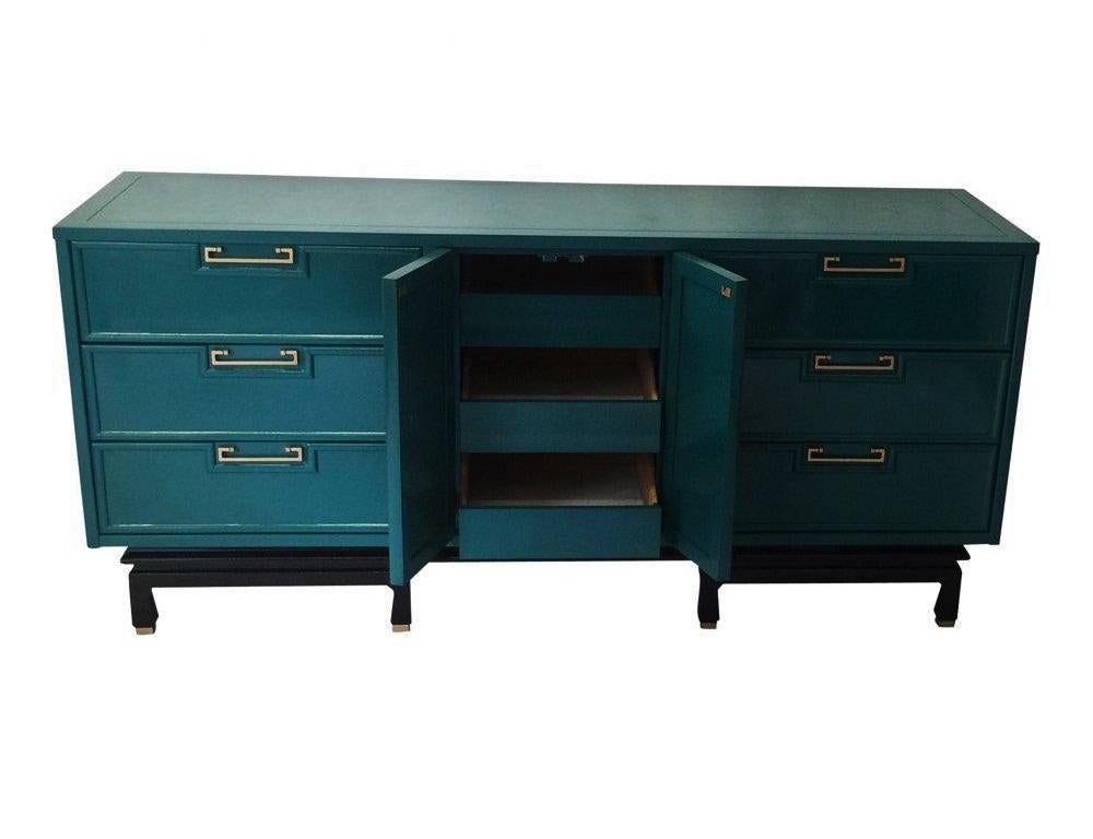 Gorgeous vintage modern American of Martinsville dresser / credenza lacquered in teal with a black base. There are nine double dovetail drawers-three of which are behind the doors in the center. The original hardware has been polished along with the