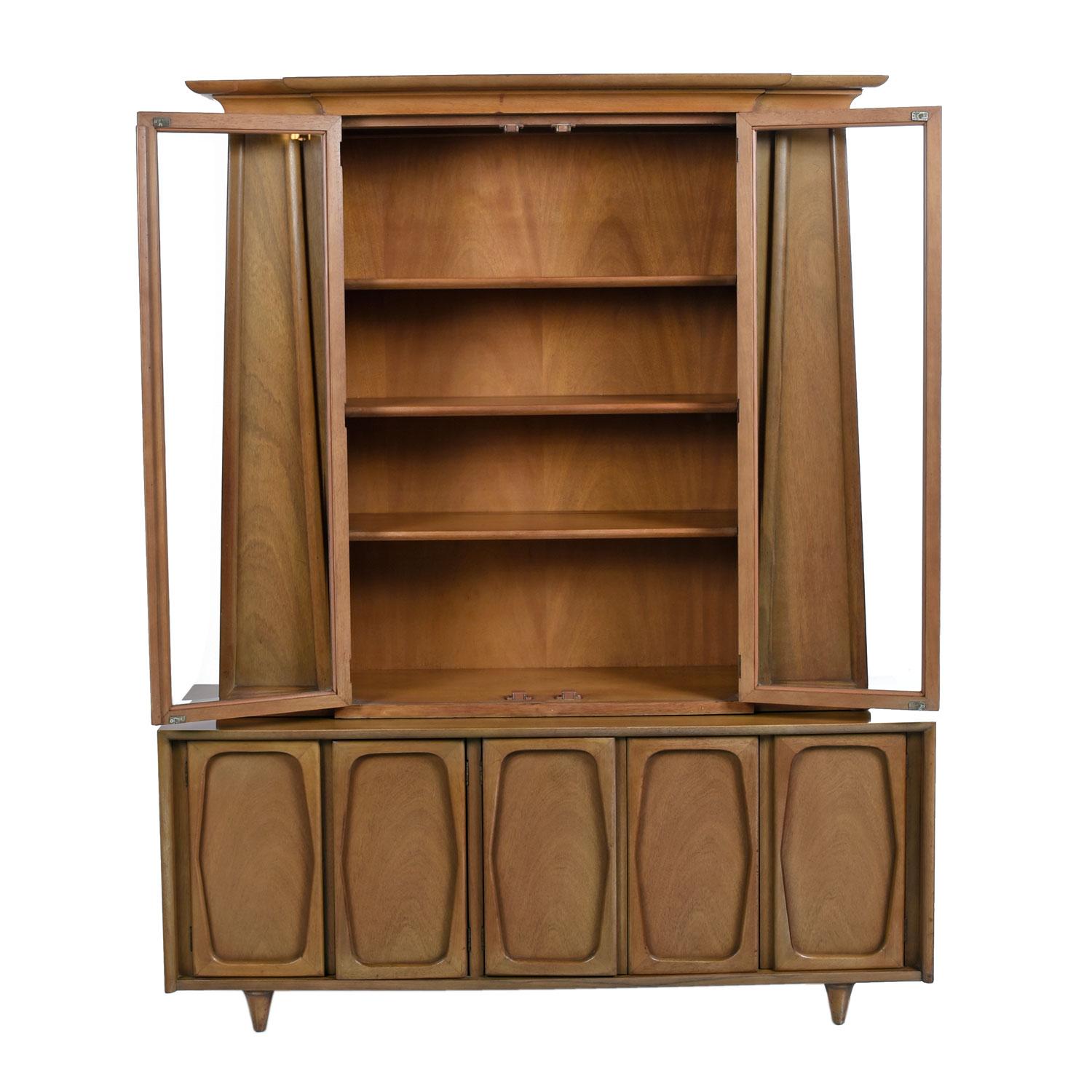 Our crew is enamoured by the unique design of this two-piece china hutch. We give respect to the heavy duty, over engineered American craftsmanship. The style is an interesting mix of Mid-Century Modern and Art Deco design. The pyramid shaped top