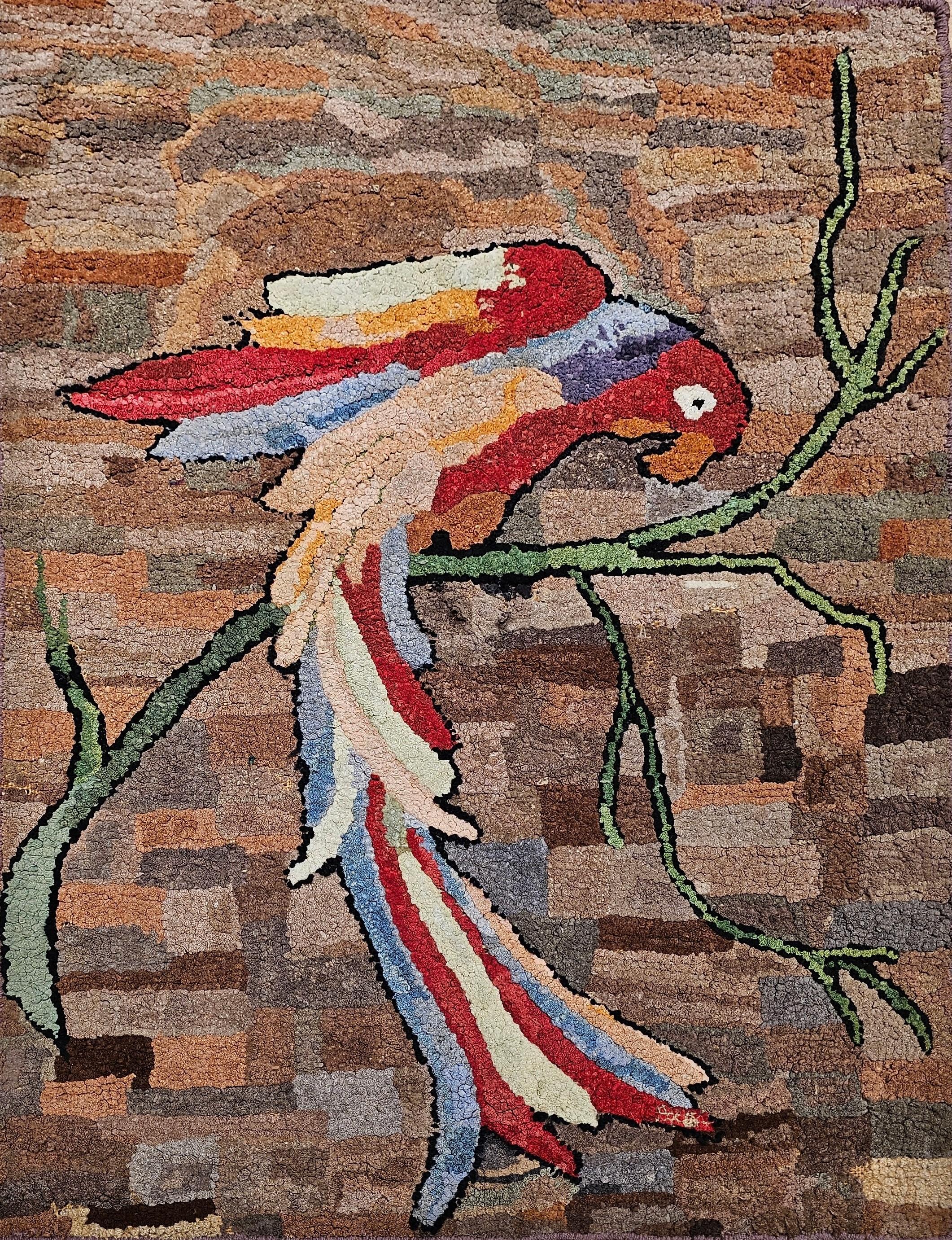 Alfombra pictórica vintage americana enganchada a mano con una maravillosa representación de un loro en la rama de un árbol.  La alfombra tiene un diseño y unos colores encantadores.   Estamos intrigados por la novedad y la imaginación del