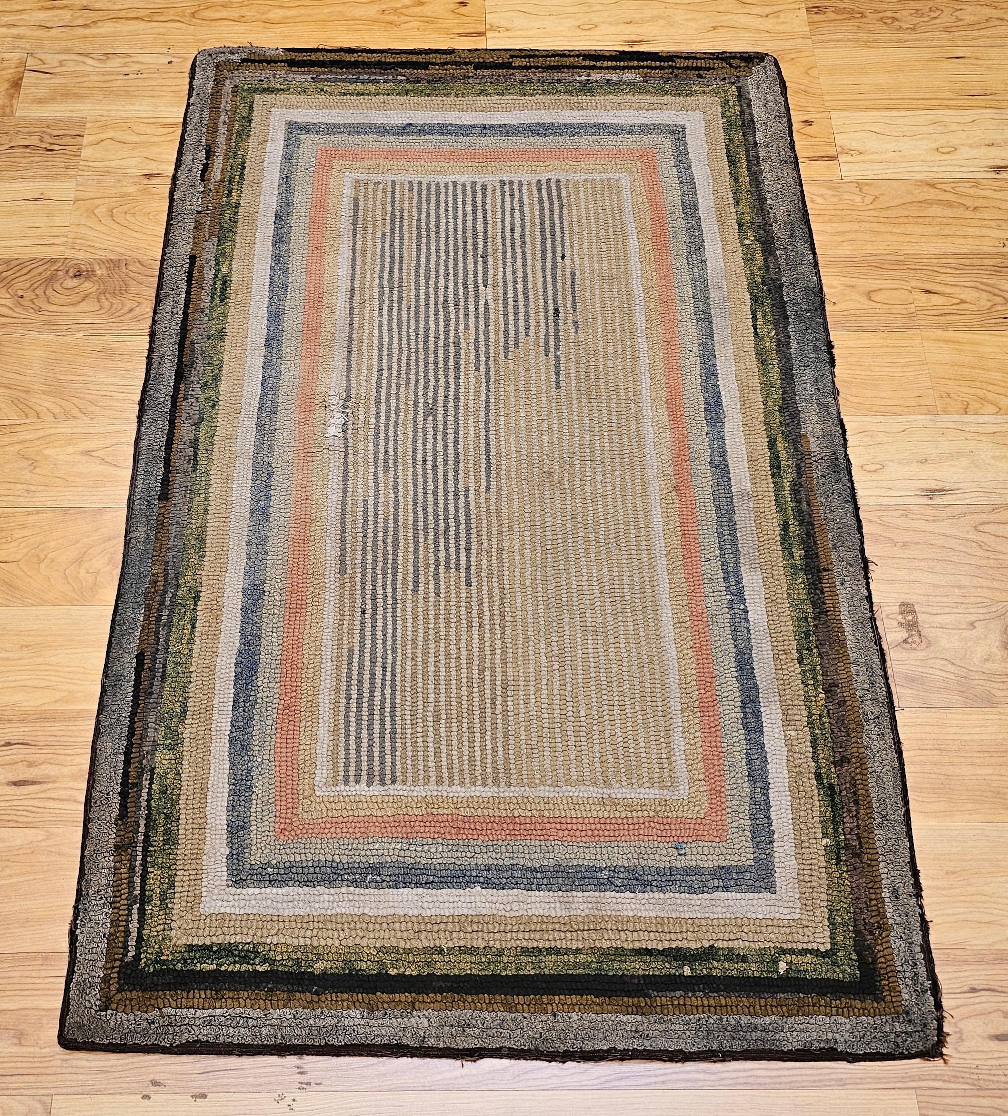 Vintage American Rag area rug in a multicolor stripe field pattern from the early 1900s.  The colors include tan, ivory, gray, brown, green, and pink. The design of the rug consists of a number of concentric rectangles in different colors with a tan