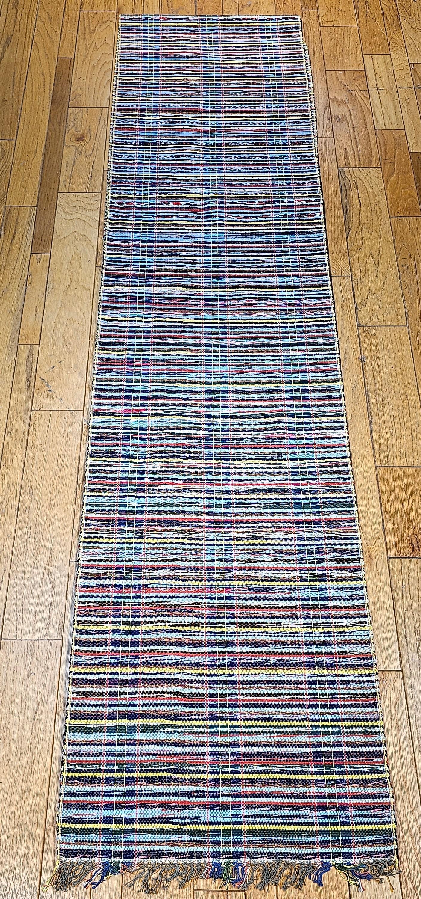Vintage American rag runner has a navy, baby blue, yellow, red, and cream color variations background  and three sets of vertical  stripes in beautiful baby blue. Custom resizing service is available for this item upon request.  The long rag runner