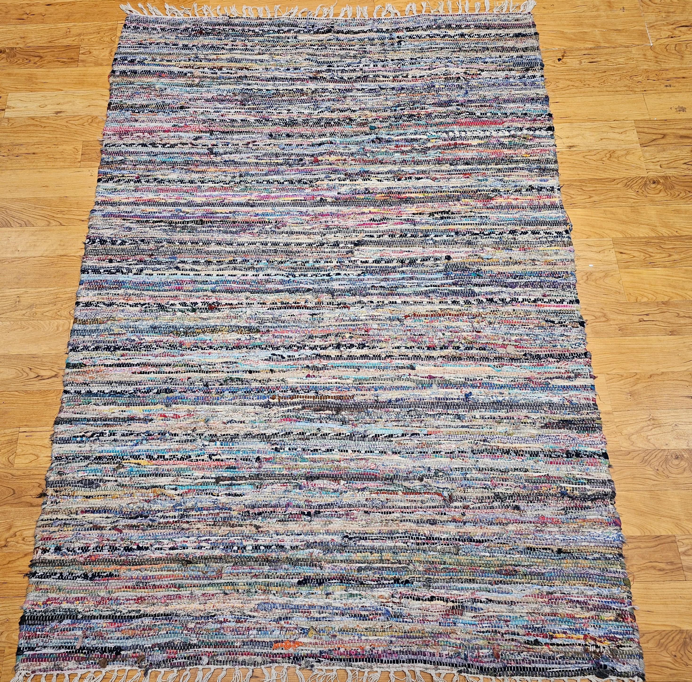 Vintage American rag area rug from the early 1900s in a multicolor stripe pattern.  Simple but beautiful design (a Amish and Shaker concept) of using old clothing material to make a useful and practical item for home use. The colors include blue,
