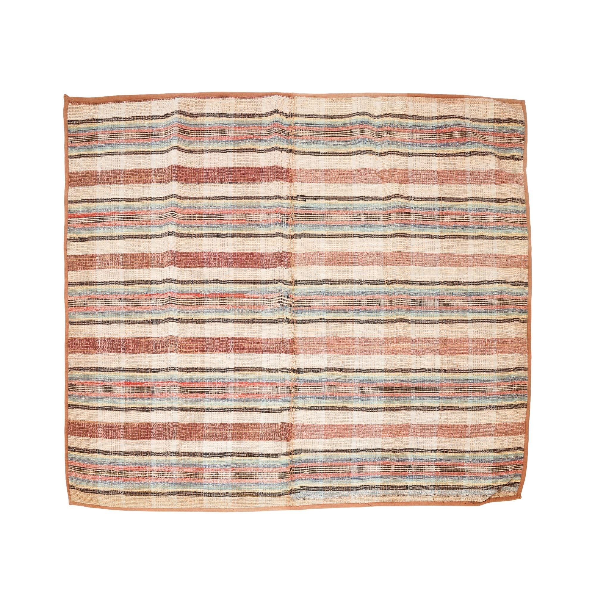 American handmade two part rag rug with bound edges. The rug pattern is organized in repeated bands of raspberry, blue, tan, and black.
American, circa 1850-1900.