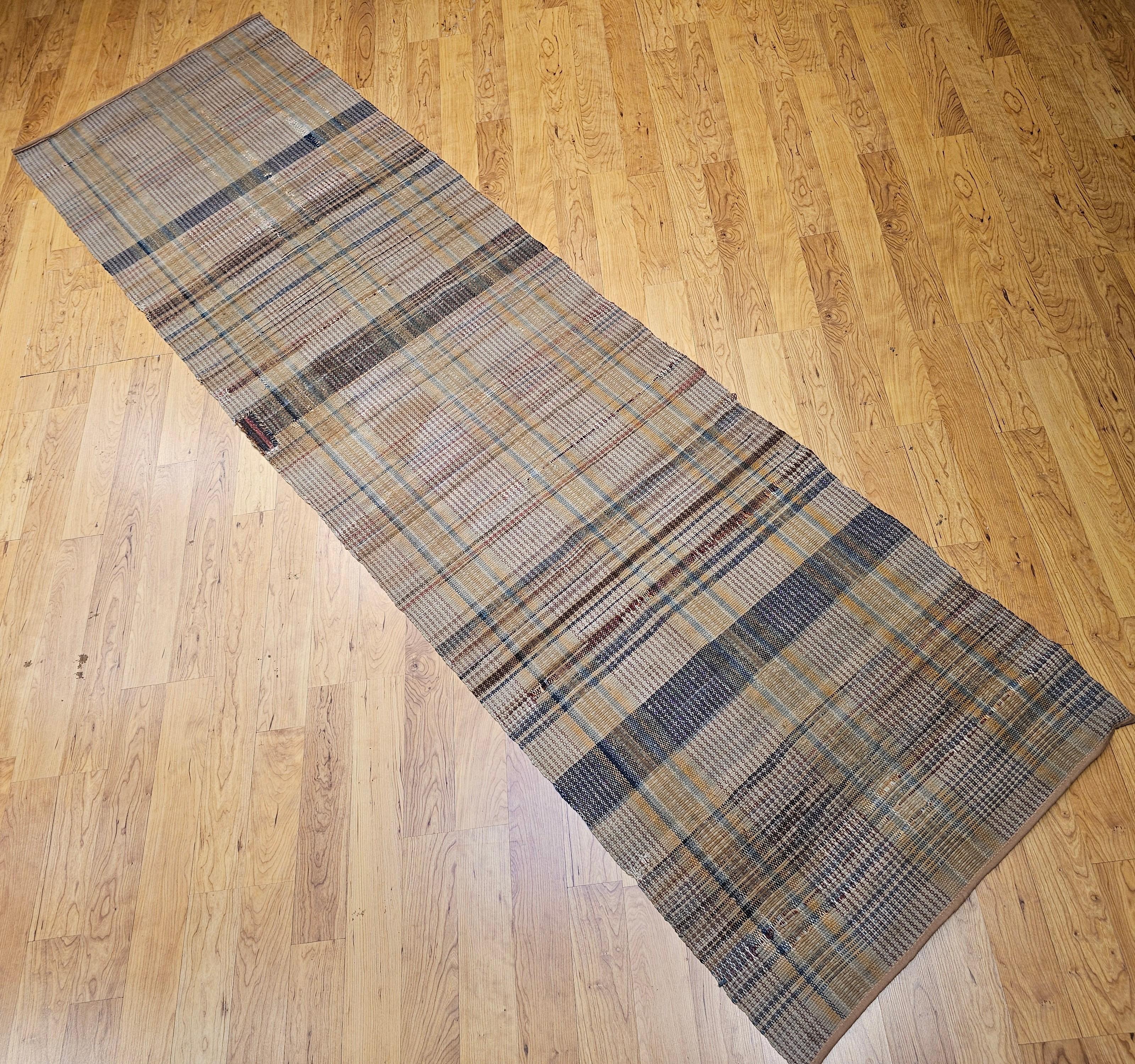 Vintage American rag runner from the early 1900s in a wonderful stripe pattern and great color.  The design of this early 20th century American rag runner consists of three end to end stripes in pale yellow and blue set on a tan color background.