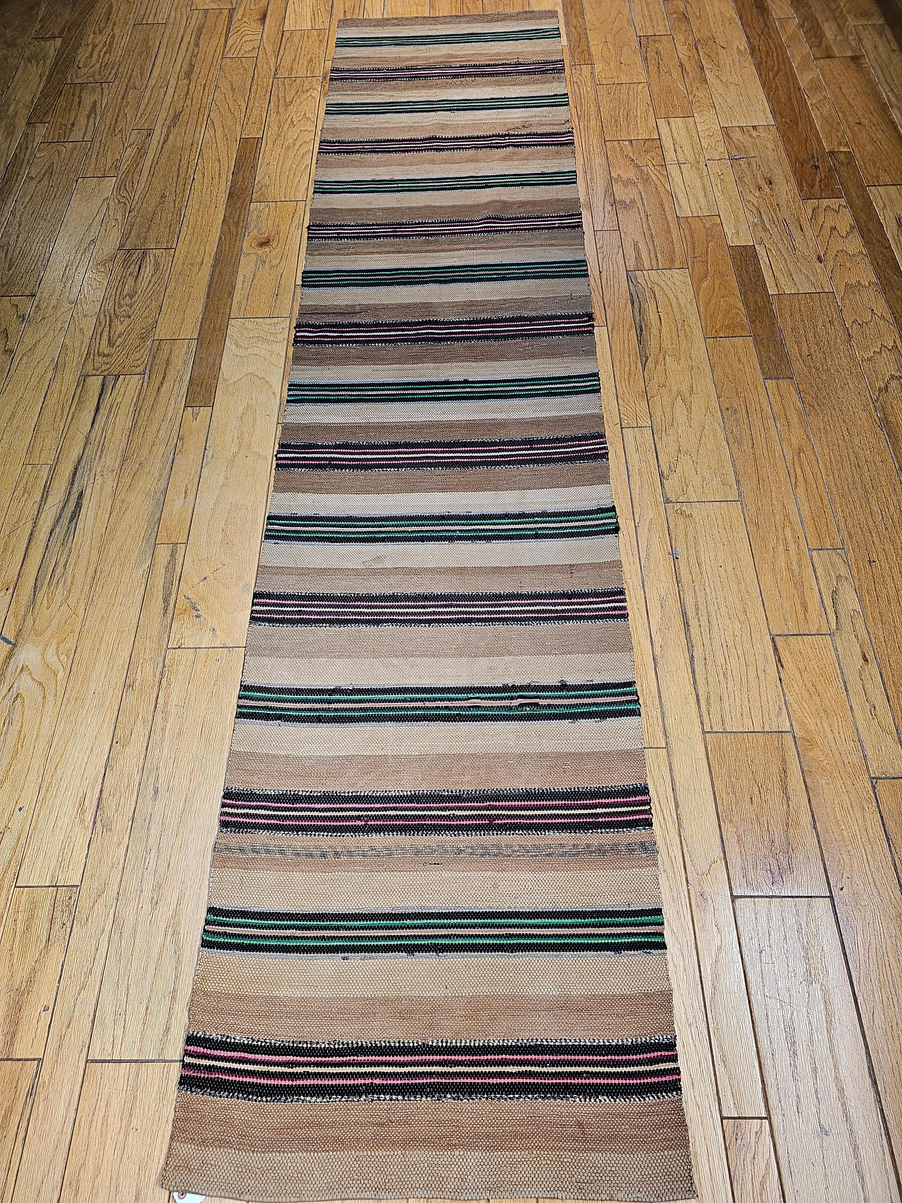 Beautiful vintage American rag runners in a natural earth tone color background of wide bands in tan and cream, separated by bright green and pink color narrow bands. This is one of the two identical runners (SKUs 1612 and 1613). Each runner is 2’