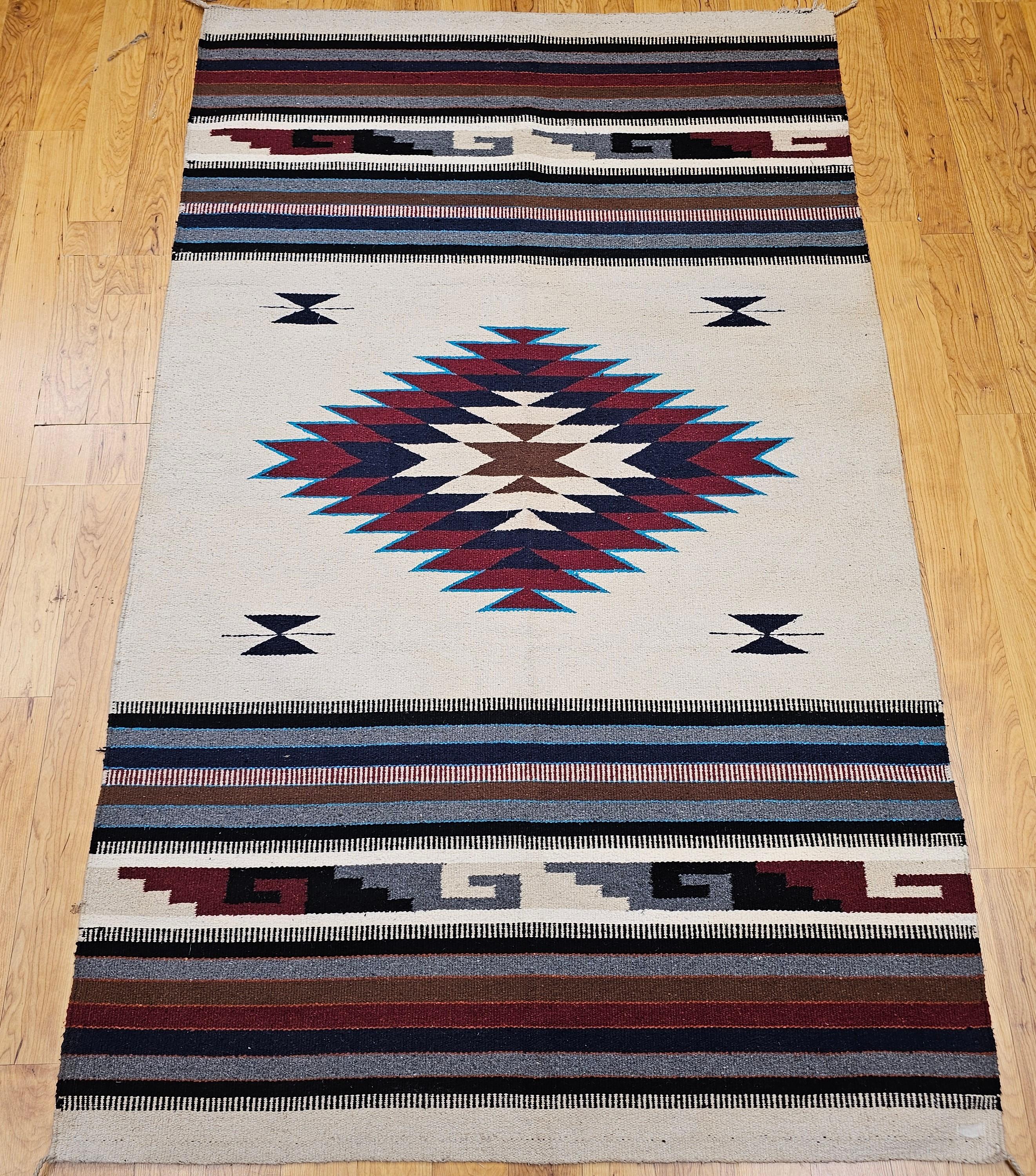 Bring authentic Southwestern charm into your space with this vintage Saltillo kilim rug, beautifully handwoven in the mid-1900s. Featuring a soft ivory background, this finely crafted textile showcases a bold central medallion in rich tones of