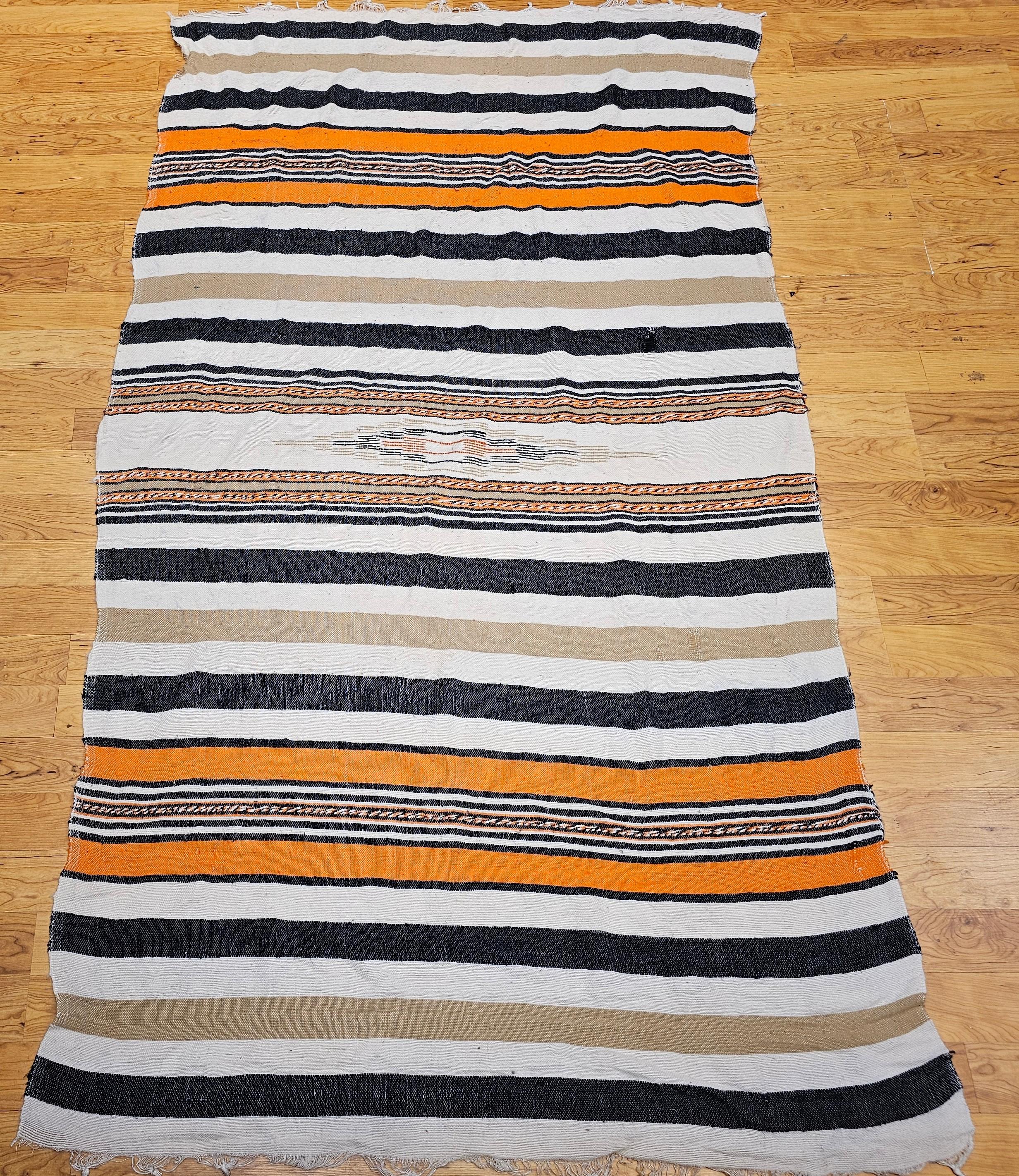 Diese alte Serape-Decke aus dem Südwesten zeigt die zeitlose Schönheit der traditionellen mexikanischen Textilkunst. Dieses im dritten Quartal des 20. Jahrhunderts gewebte Stück weist ein abwechselndes Bandmuster in warmen Elfenbein-, Hellbraun-,