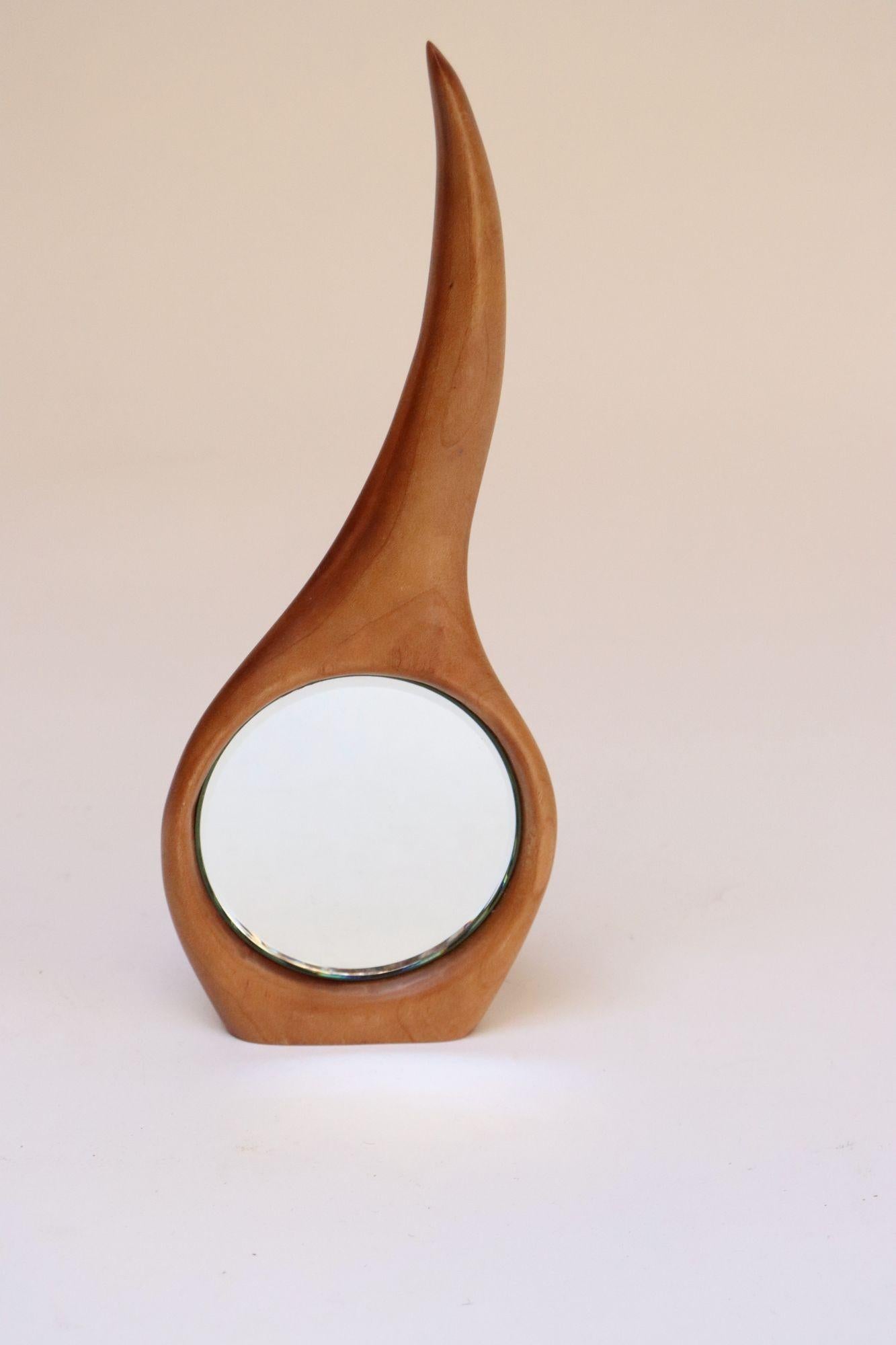 Elegante toeletta/specchio portatile composto da un vetro a specchio incastonato sostenuto da una cornice in ciliegio massiccio intagliata a mano e dalla forma organica (ca. 1960, USA).
Un design unico e ingegnoso, realizzato con una superficie