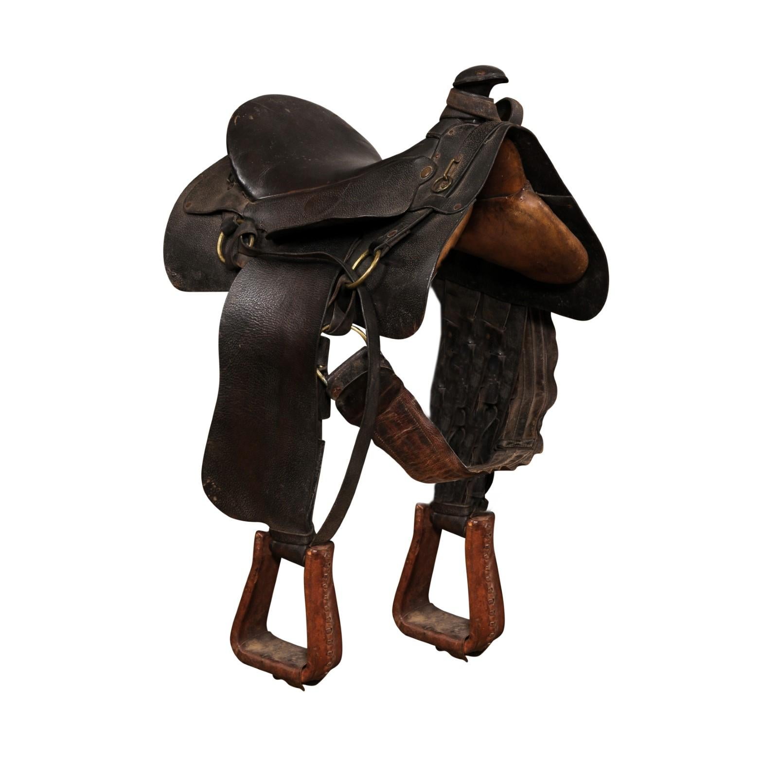 An American Western style leather saddle from the 20th century, with dark brown/black seat, jockey, fender, horn and lighter brown stirrups. Handcrafted in America during the 20th century, this leather Western style saddle boasts a nice patina