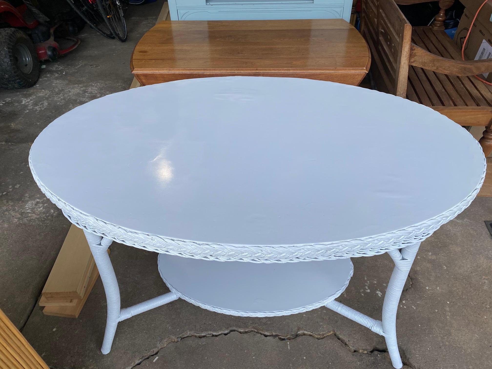 A charming oval white wicker dining table made by Merikord - The American Wicker Company , with underside plaque.  Bottom tier is 8
