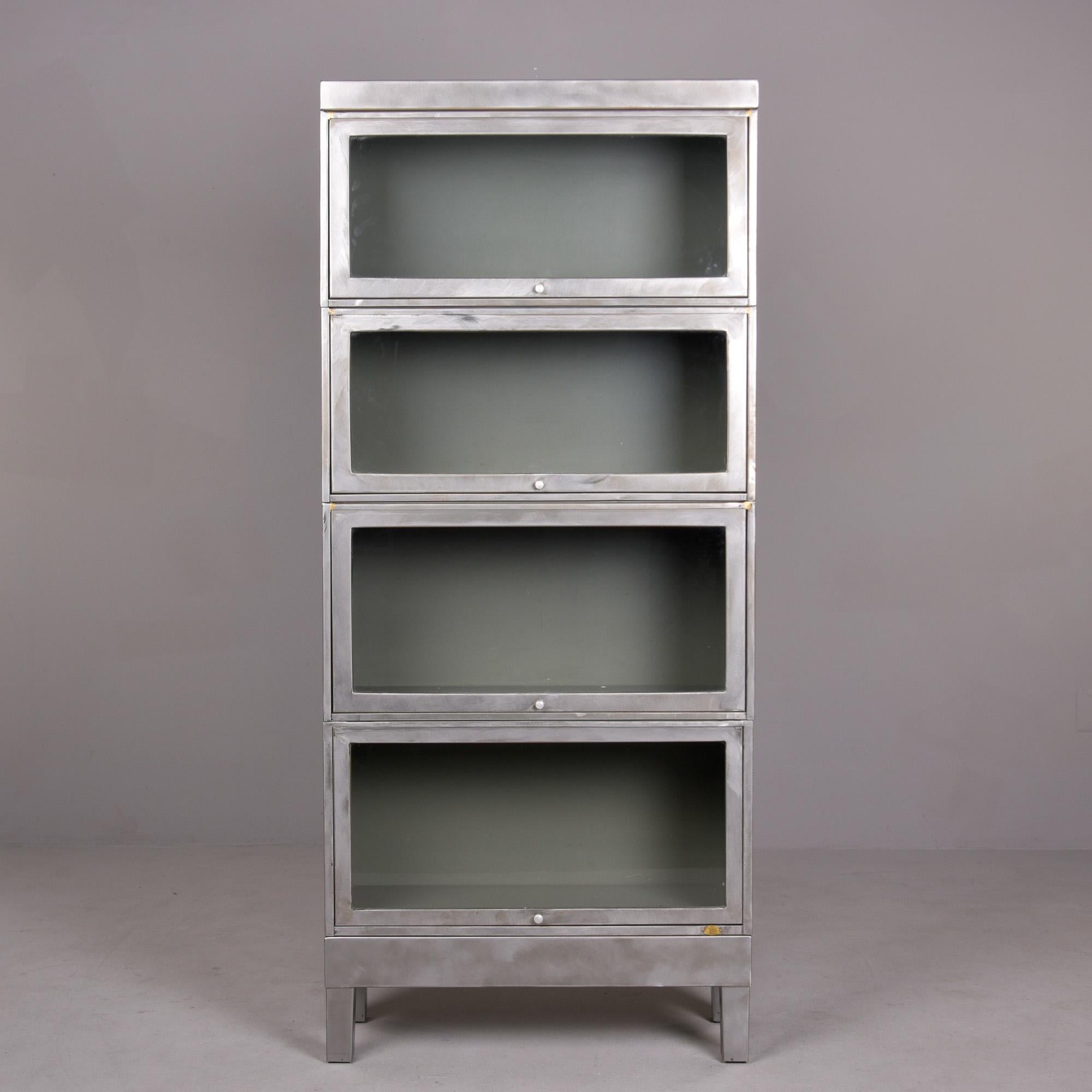 Trovata negli Stati Uniti, questa libreria industriale a quattro sezioni in metallo e vetro risale agli anni Quaranta. Un pezzo pratico e decorativo con un look industriale senza tempo. Il corpo del mobile in acciaio spazzolato ha una base a quattro