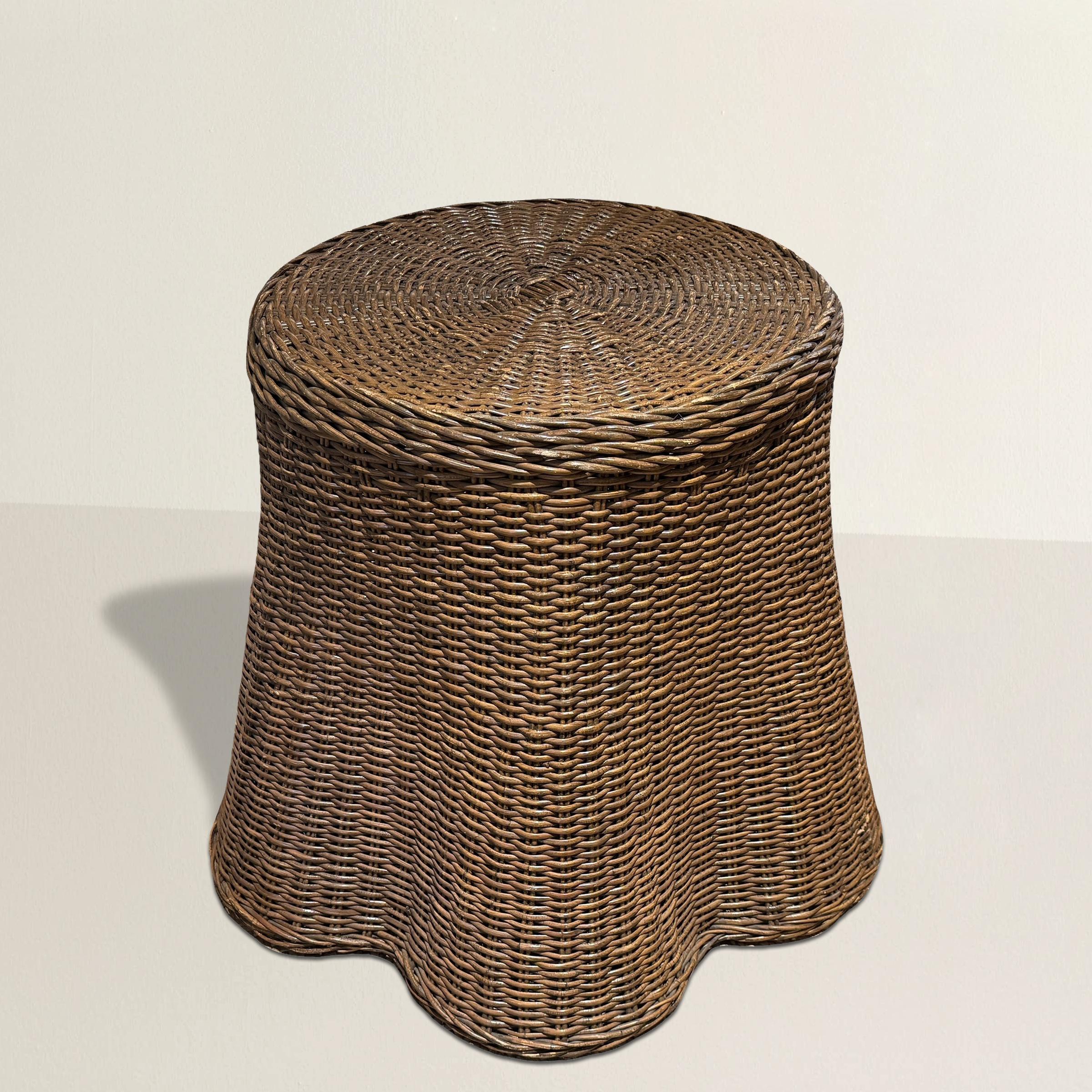 Une fabuleuse table vintage en osier tressé américain du 20e siècle, conçue avec un jeu artistique sur la texture et la forme. Ses côtés ondulés imitent le doux drapé d'une nappe fluide, donnant l'illusion d'une table à jupe, entièrement fabriquée