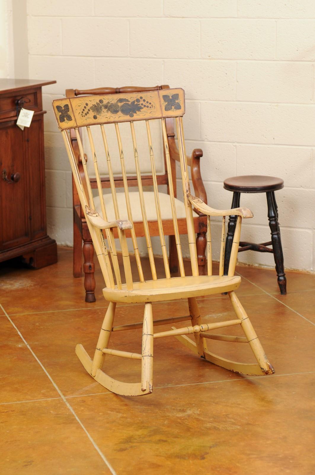 Yellow painted American rocking chair with green painted floral decoration and spindle back, 20th century.