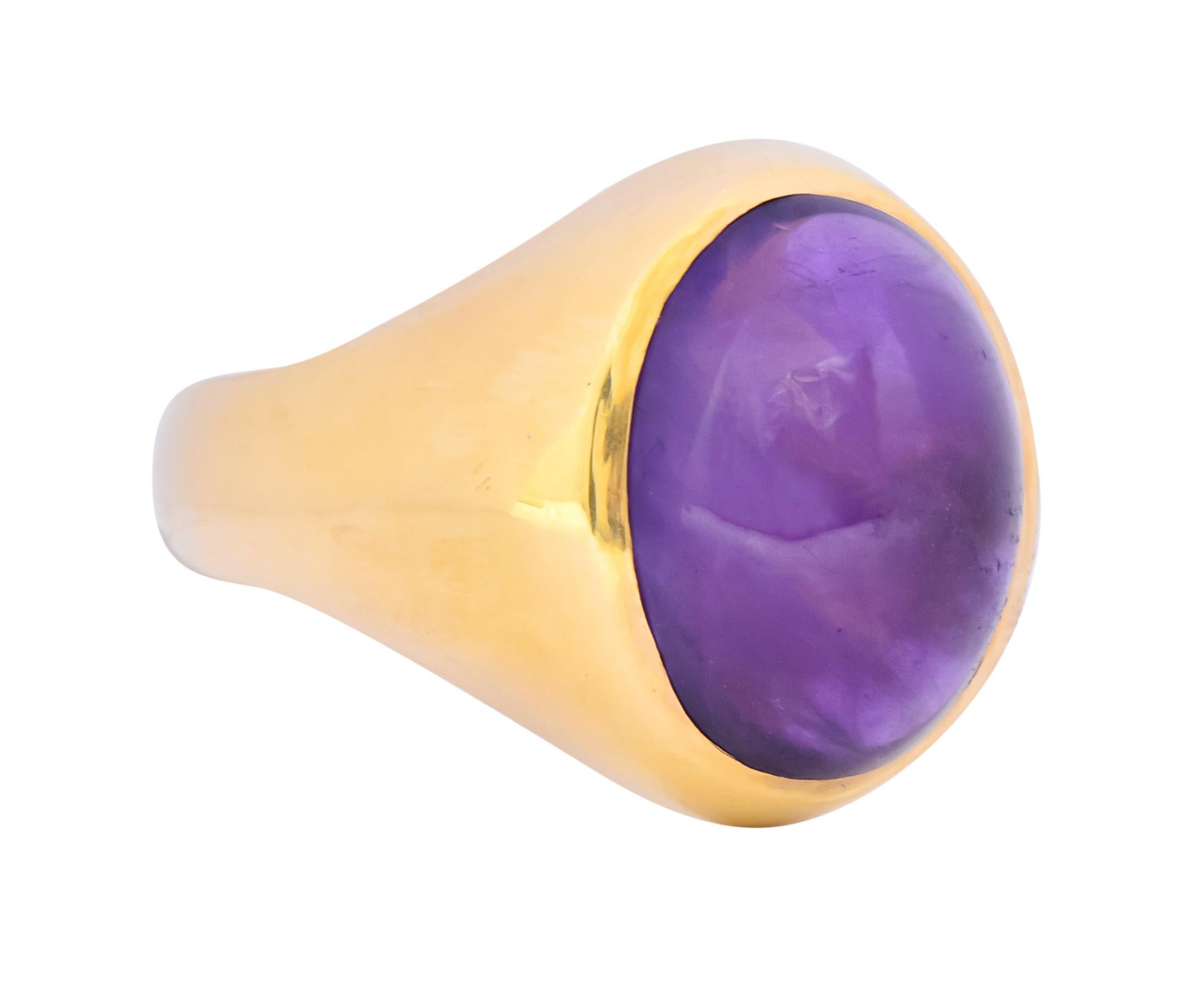 Centering an oval amethyst cabochon measuring approximately 3/4 x 9/16 inch, translucent and a rich medium-dark purple

Bezel set in a polished gold surround with tapered shoulders

Tested as 14 karat gold

Ring Size: 9 1/2 & sizable

Top measures: