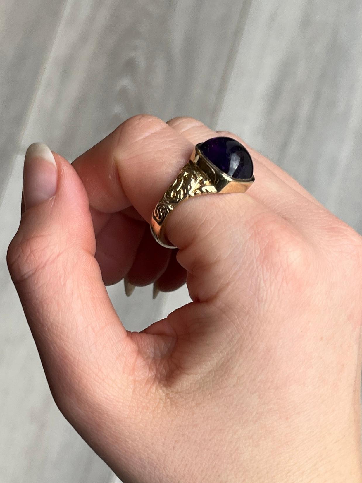 This glossy and bright purple amethyst stone is surrounded by a chunky frame of gold and the shoulders are moulded and ornate. Modelled in 9ct gold. Hallmarked London 1966.

Ring Size: U or 10 
Stone Diameter: 12.5mm 
Height off finger: 8mm

Weight: