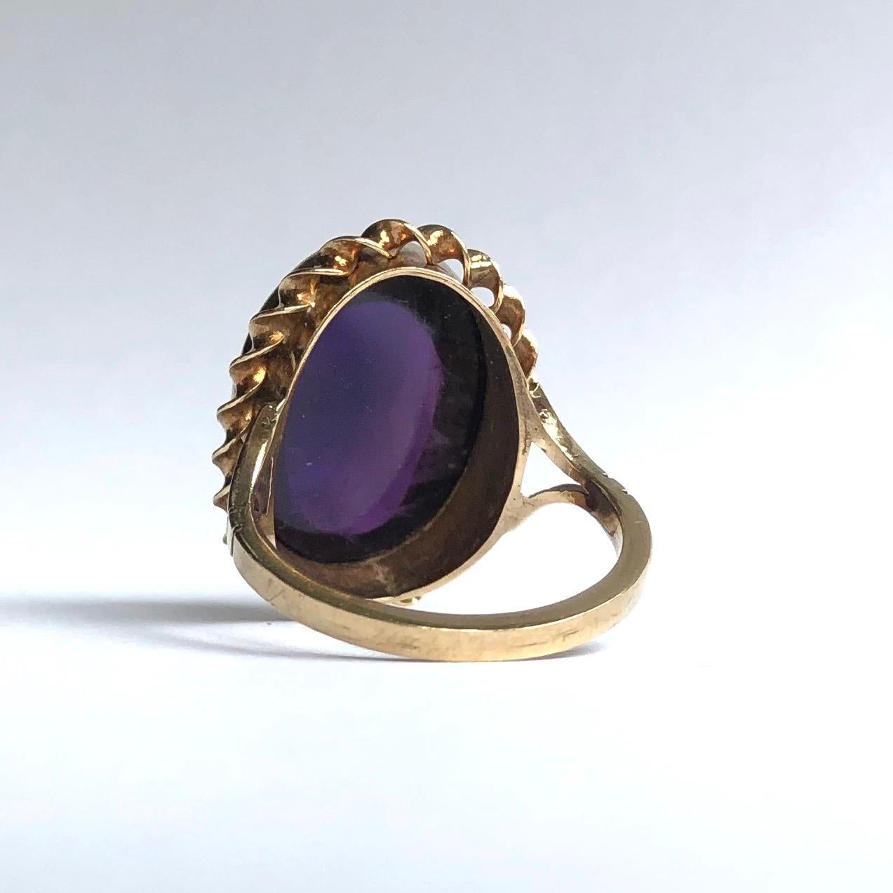 This gorgeous cocktail ring holds a large cabochon amethyst which is glossy and bright purple. Around the stone is a twisted gold frame and this then leads to split shoulders. 

Ring Size: L or 5 3/4 
Stone Dimensions: 21 x 16mm 

Weight: 5.26g
