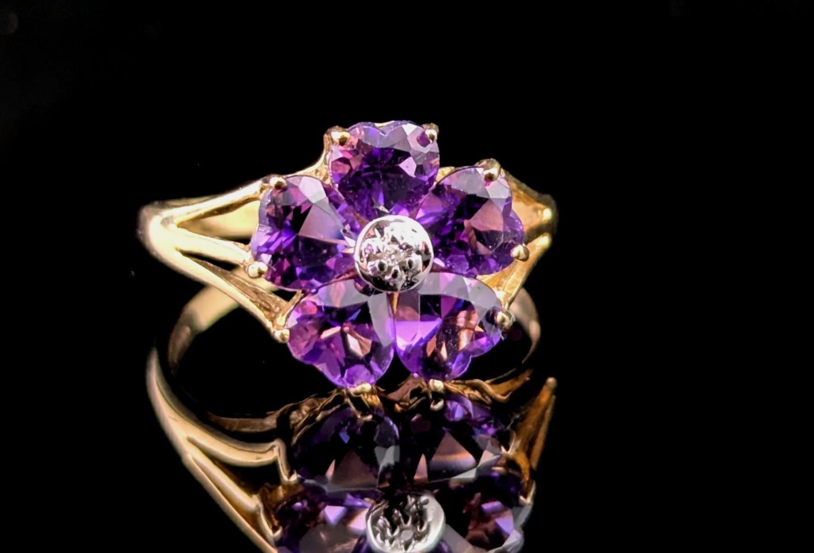 A gorgeous vintage 9ct Amethyst and Diamond flower ring.

This beautiful piece features rich and deep purple, heart cut amethyst stones arranged around a sparkling brilliant cut diamond which is set into a cool sterling silver bezel setting.

The